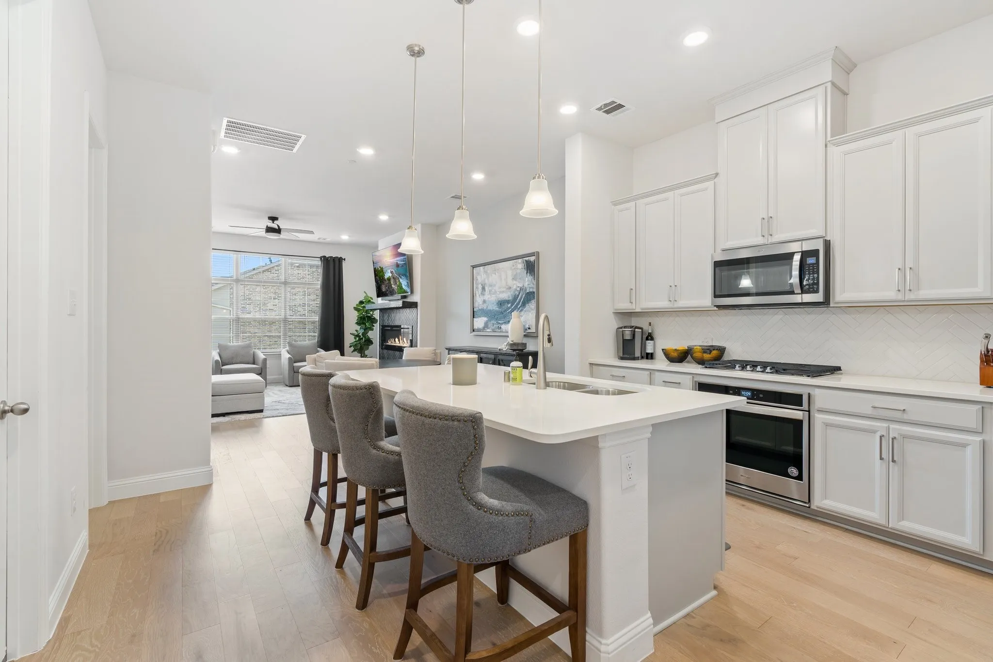Kitchen with a kitchen island with sink, tasteful backsplash, light hardwood / wood-style floors, and appliances with stainless steel finishes