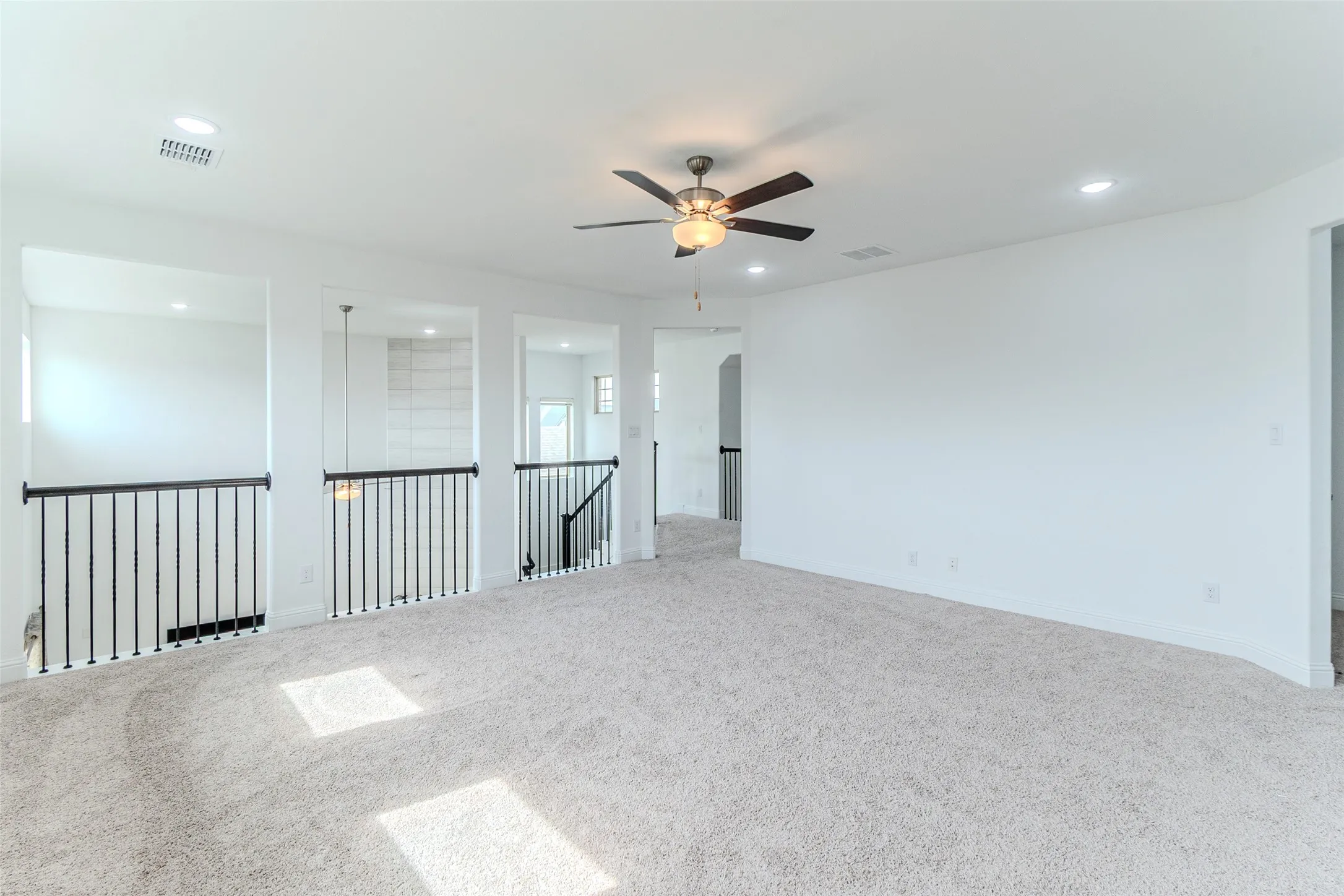 Spacious carpeted area with a ceiling fan and recessed lighting