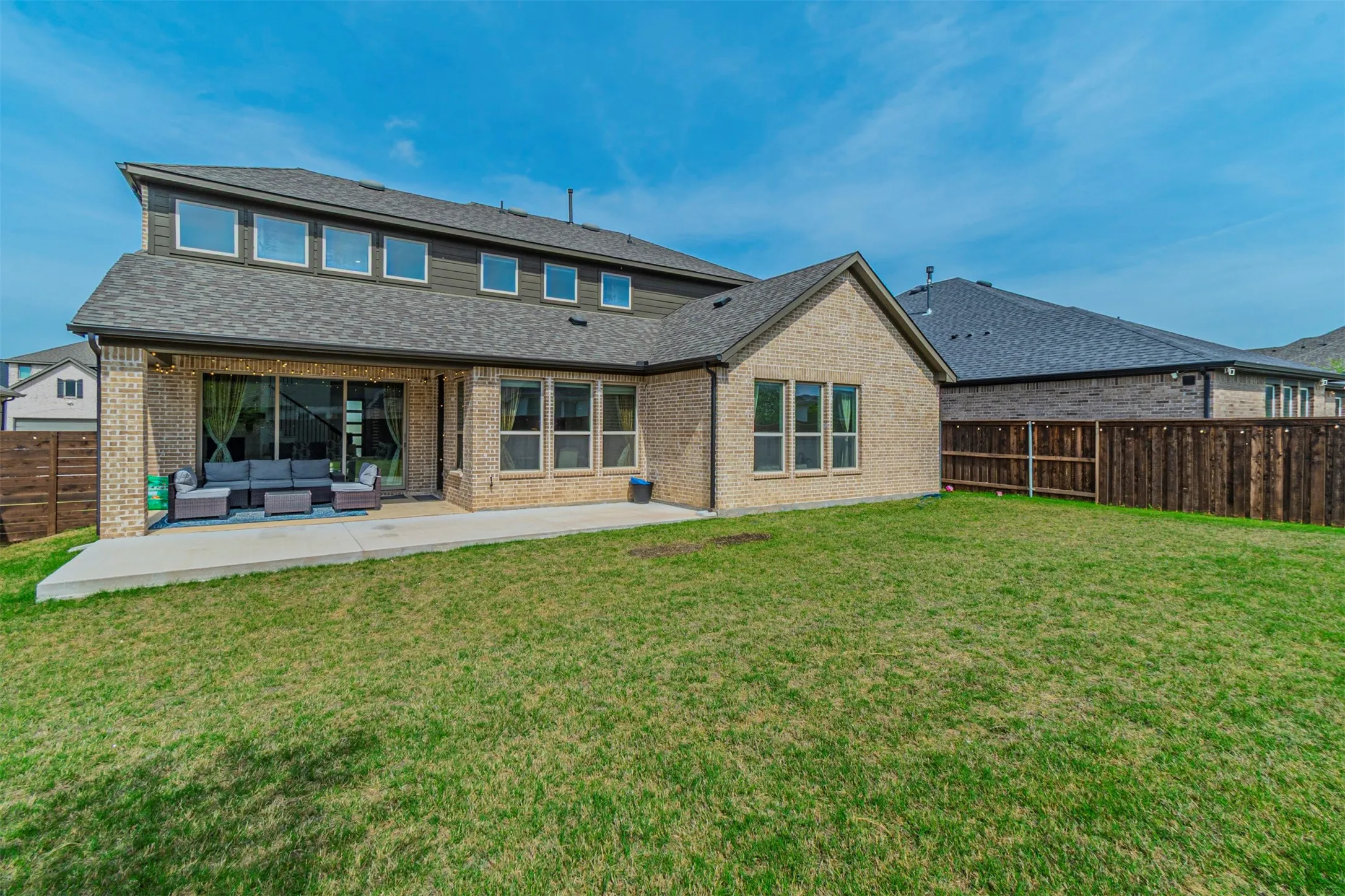 Expansive backyard featuring a manicured lawn, a large concrete patio, and a privacy fence