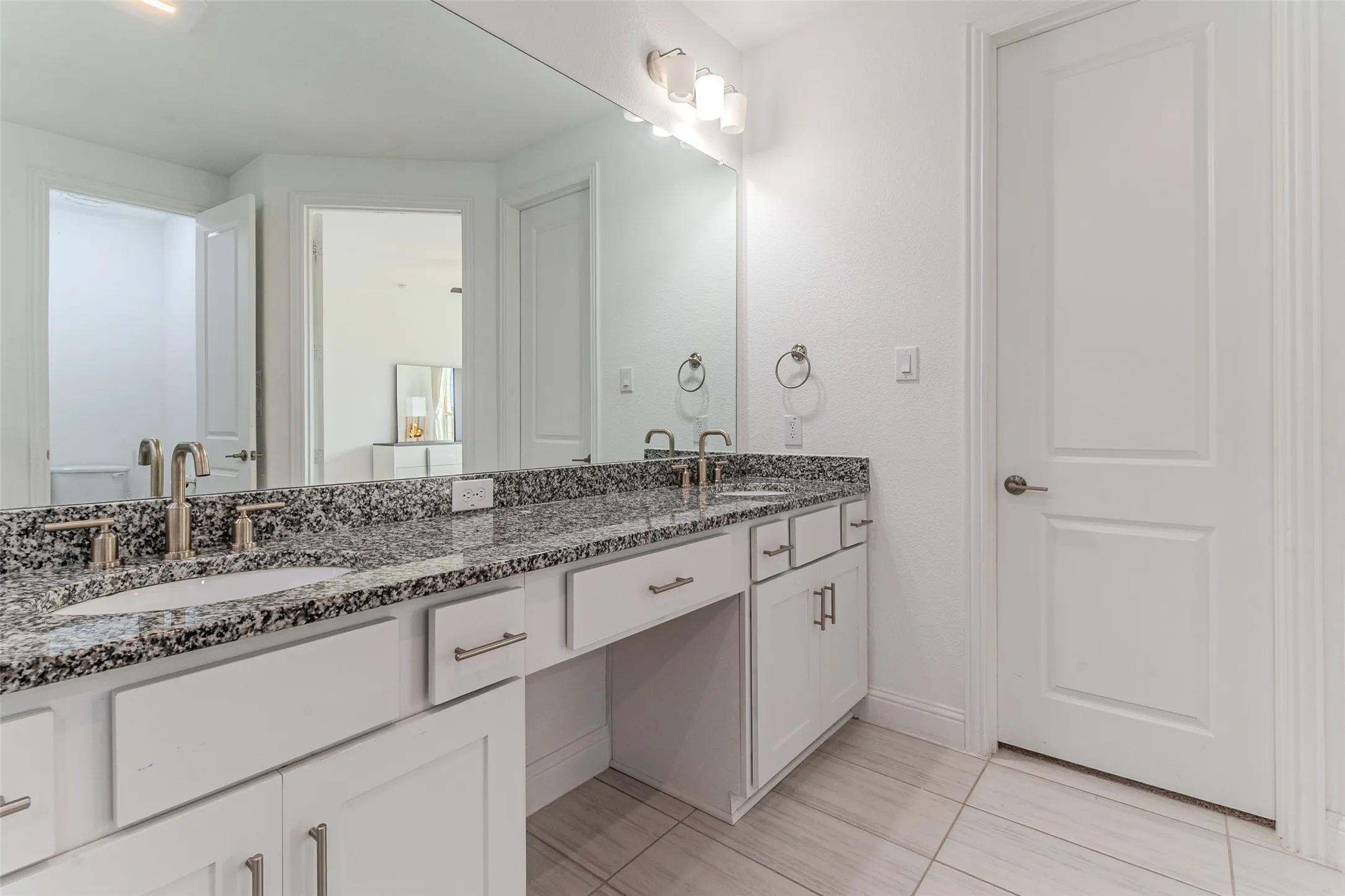 Double vanity featuring stone countertops, undermount sinks, and brushed nickel fixtures
