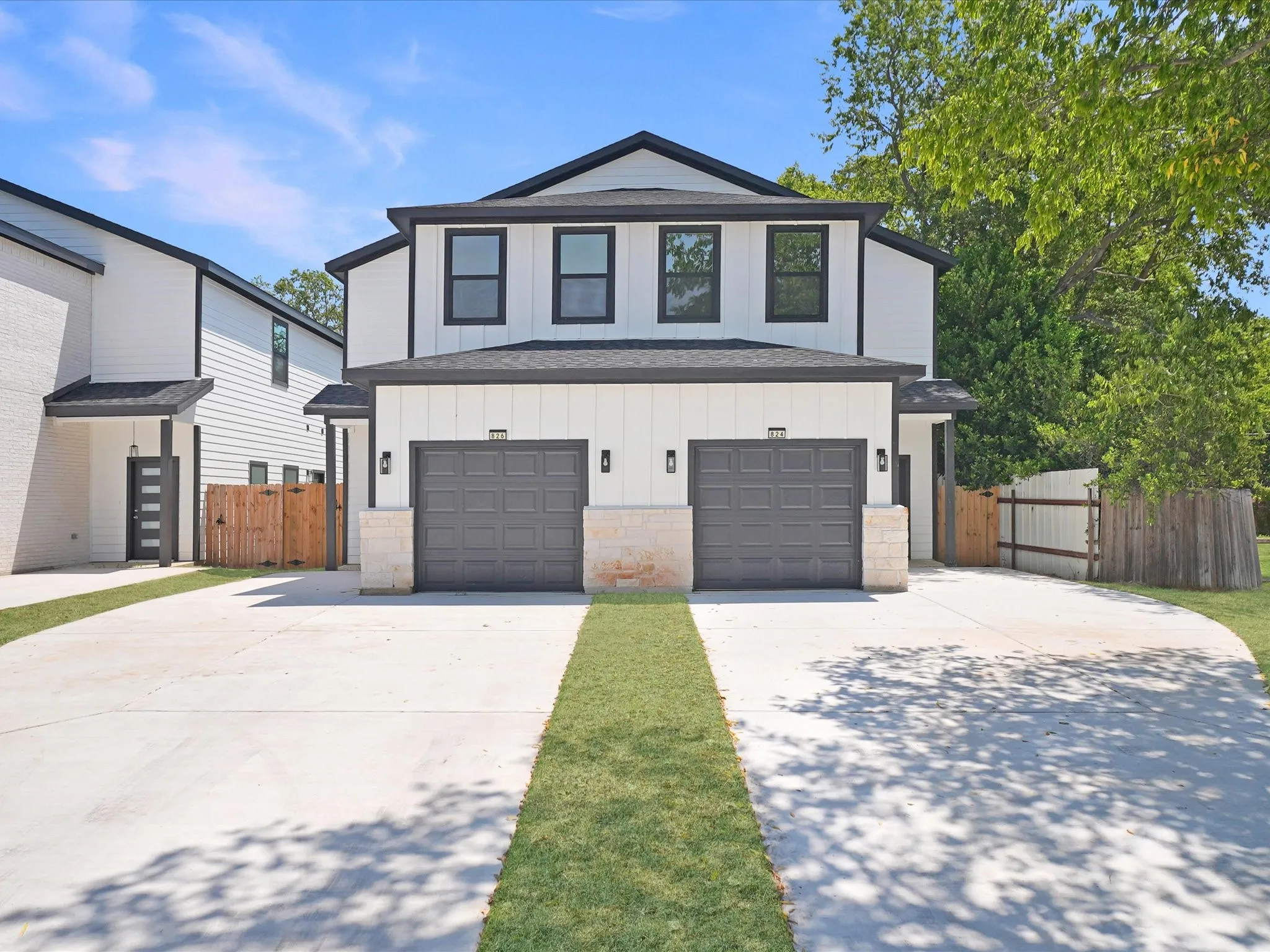 White vertical siding exterior with black trim and two attached garage doors