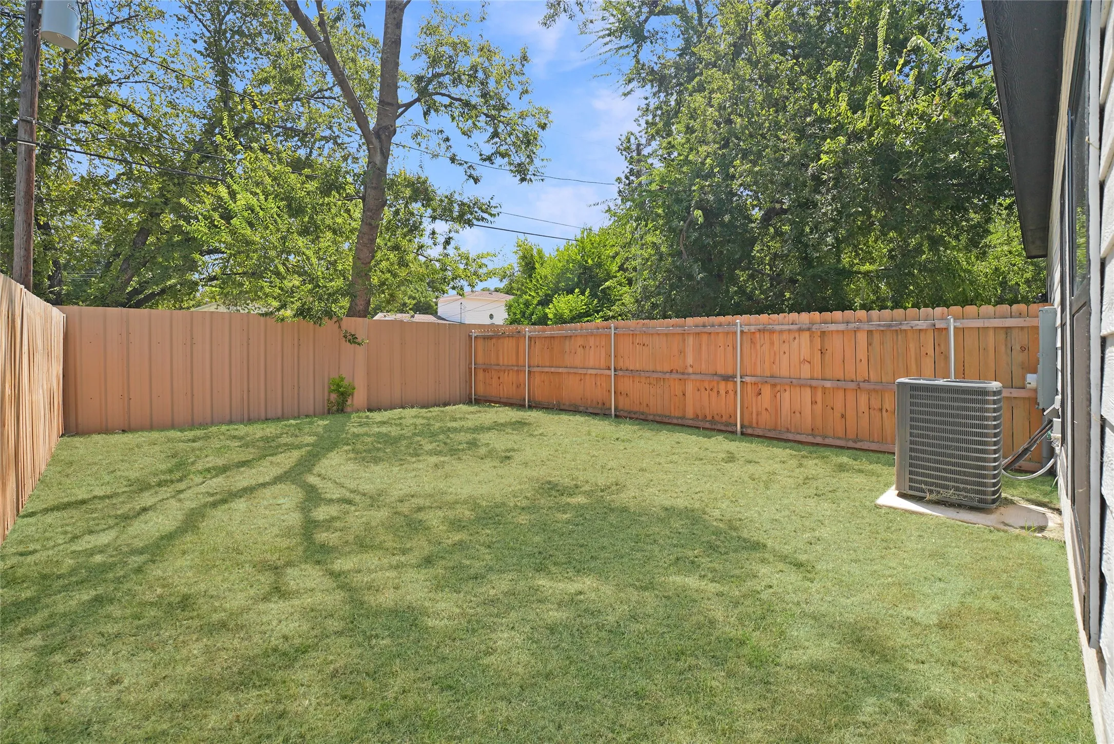 Expansive rear yard featuring a manicured lawn and wood fencing