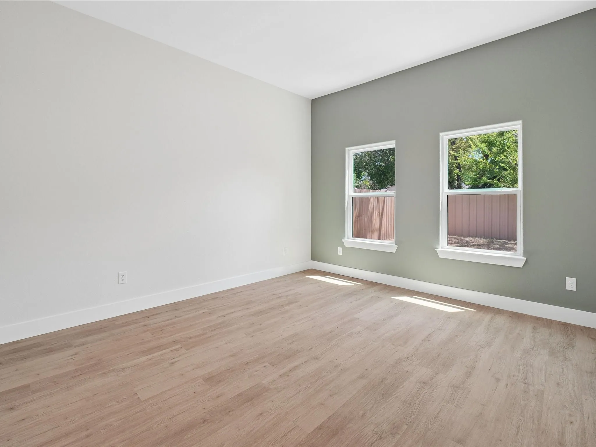 Wood-finish flooring, dual windows with white trim, and a two-tone wall treatment