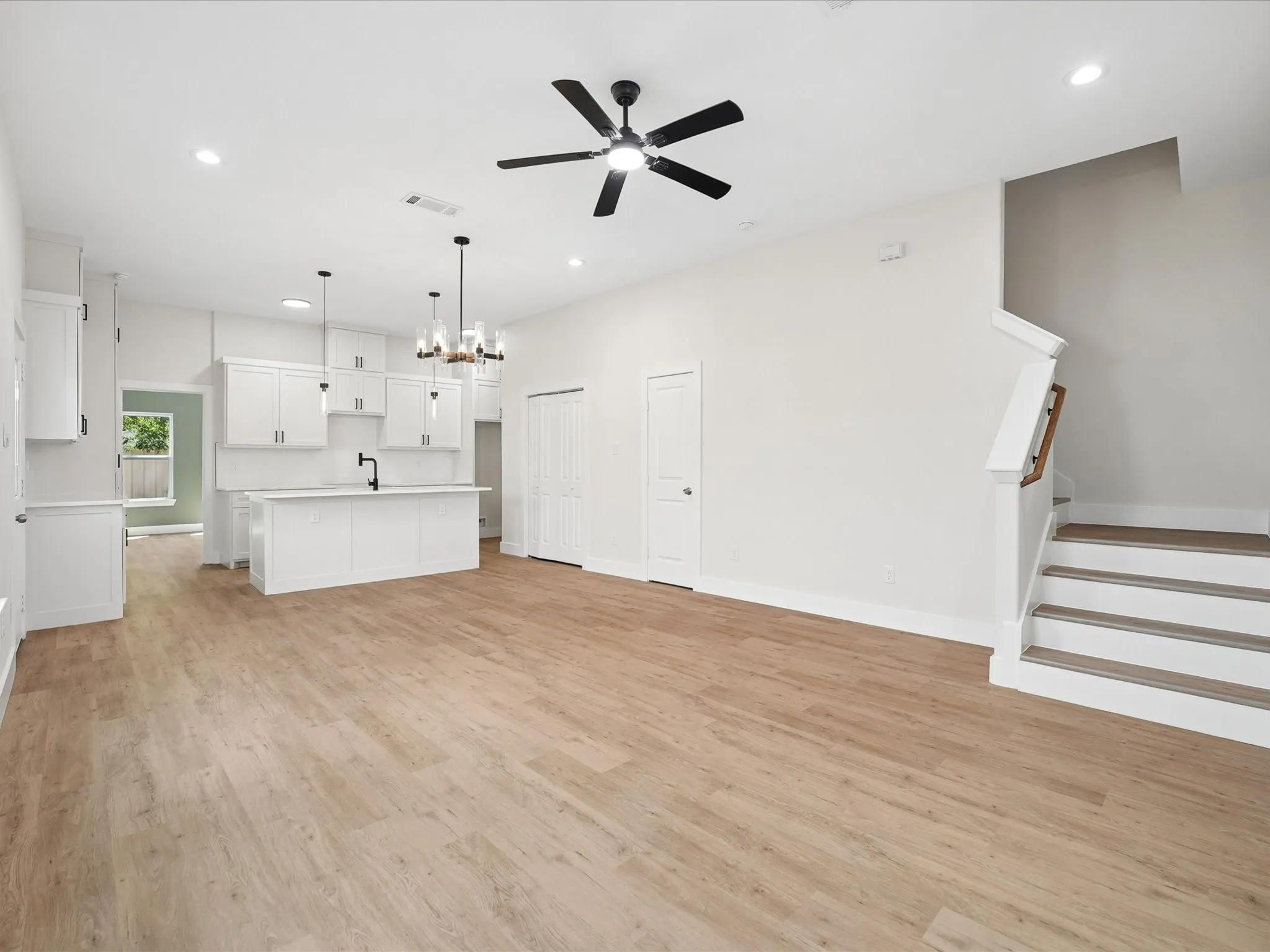 Open-concept living space with wood-finish flooring, recessed lighting, and a contemporary ceiling fan