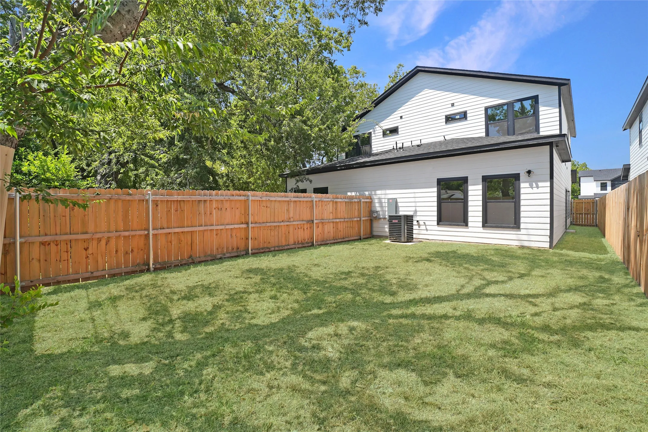 Expansive grassy yard with wood fencing and white horizontal siding