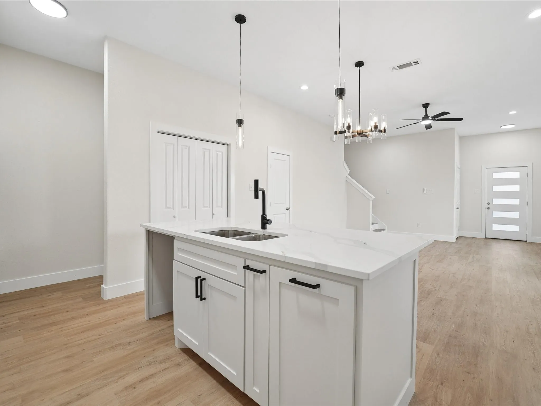 Kitchen island featuring white cabinetry, a dual basin sink, and a black gooseneck faucet