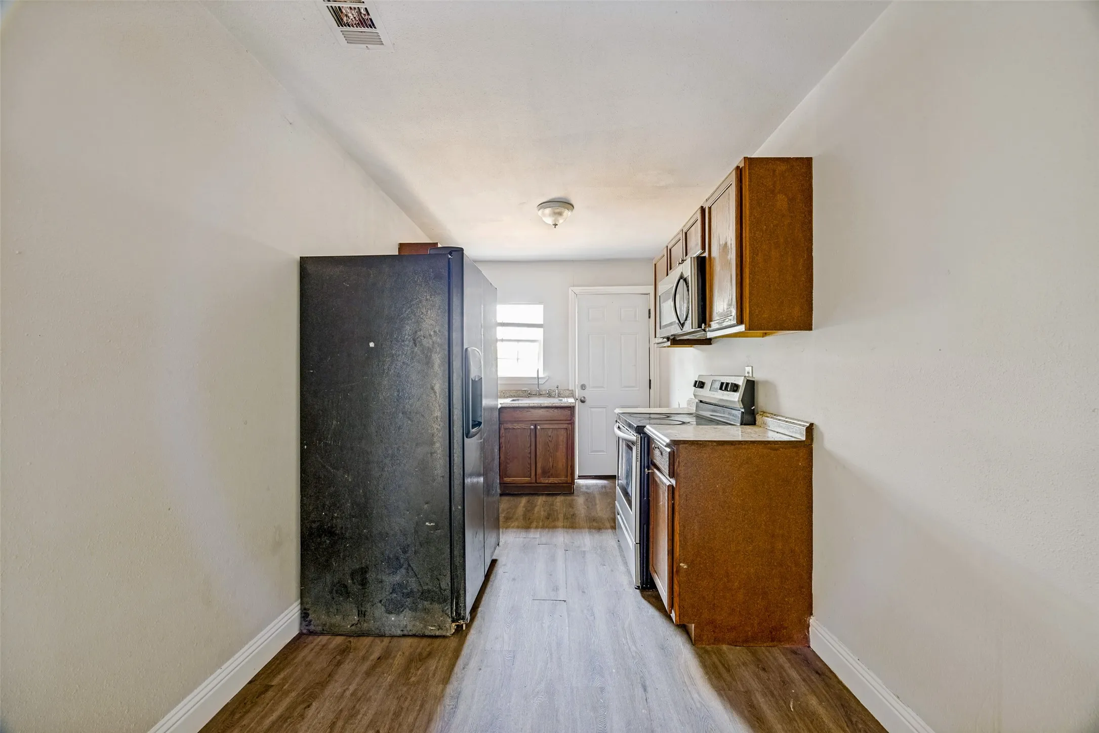 Wood-finish flooring throughout, wood cabinetry, stainless steel range, and built-in microwave