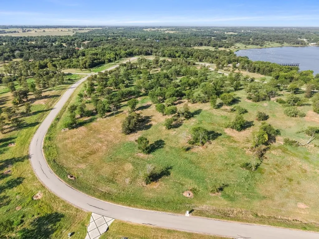 Expansive land parcel with mature trees and paved roadway access.