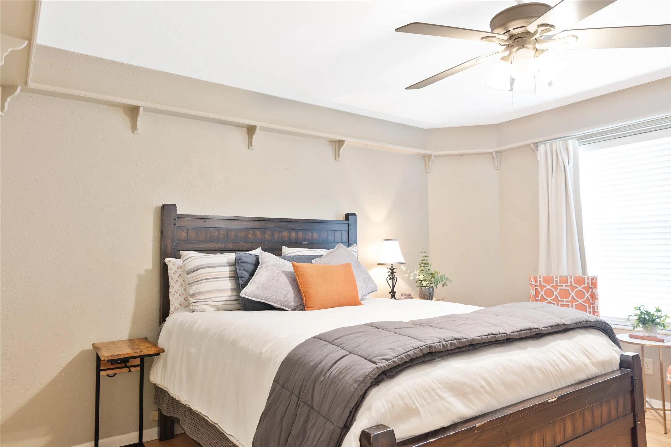 Recessed ceiling with decorative corbels, wood-finish flooring, and a ceiling fan with integrated lighting