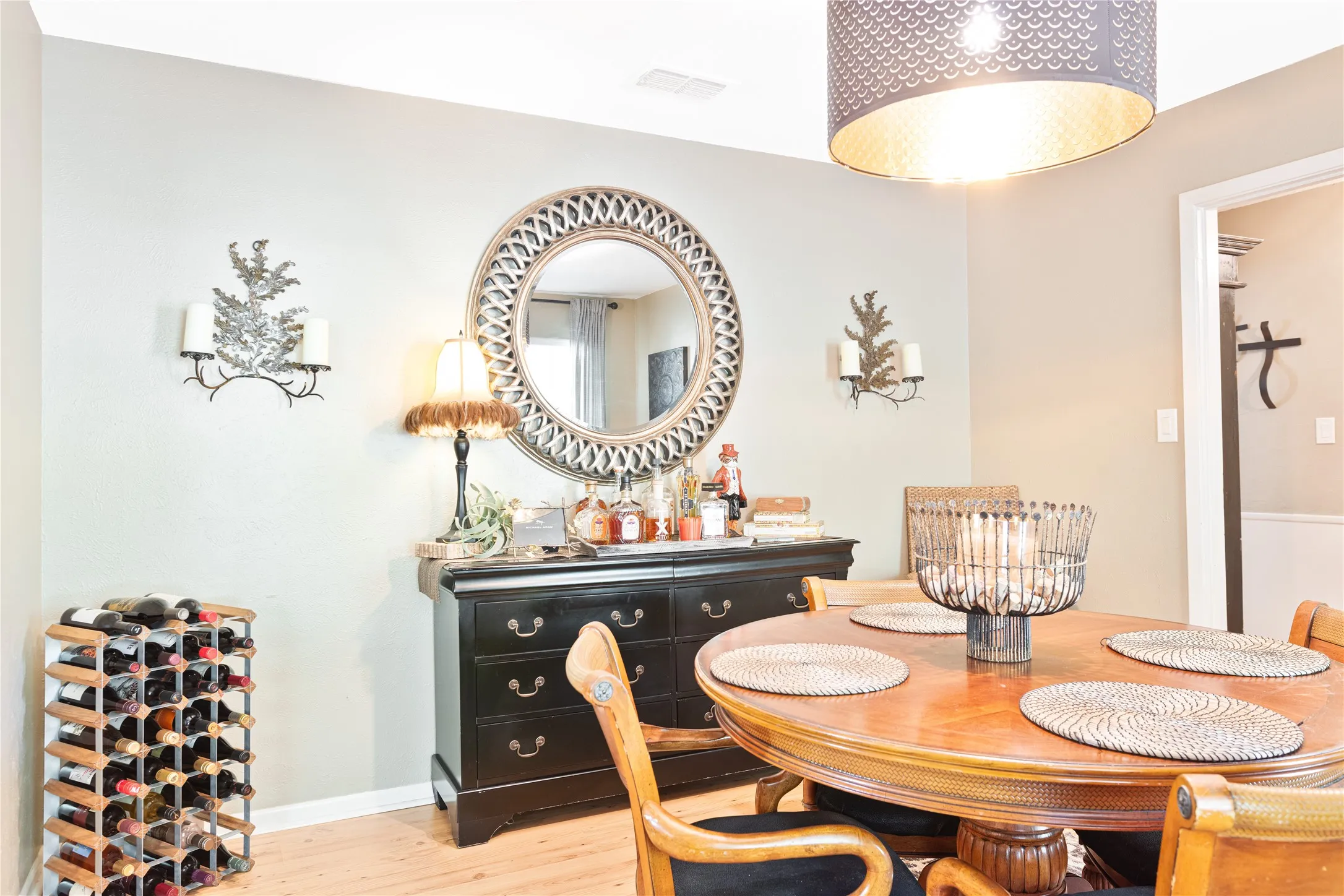 Light wood-finish flooring, accent wall sconces, and overhead lighting fixture