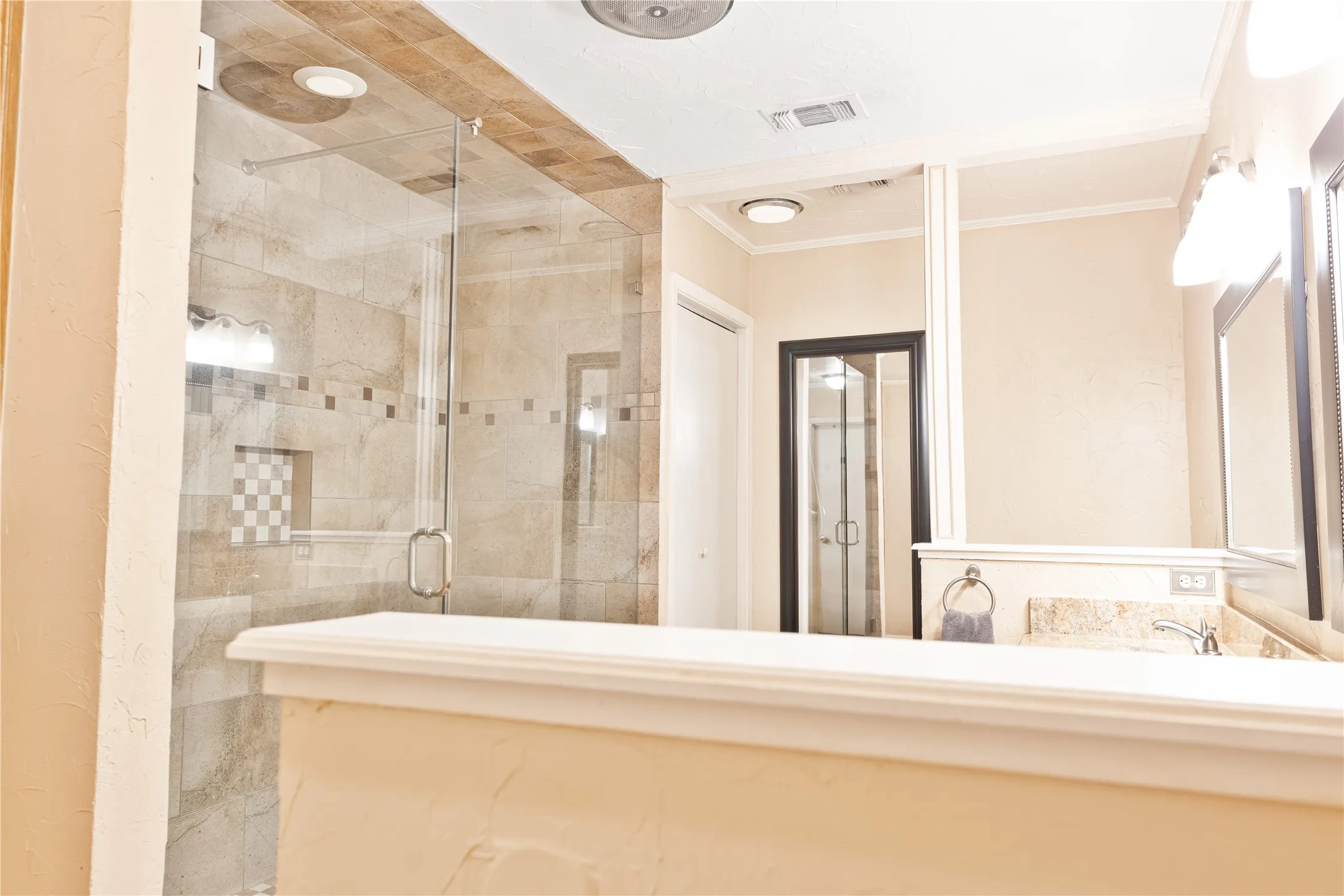 Glass-enclosed shower with tile surround and built-in niche