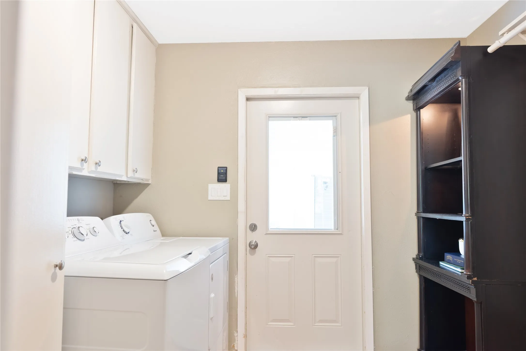 Laundry area with white upper cabinetry and a rear entry door with a window insert