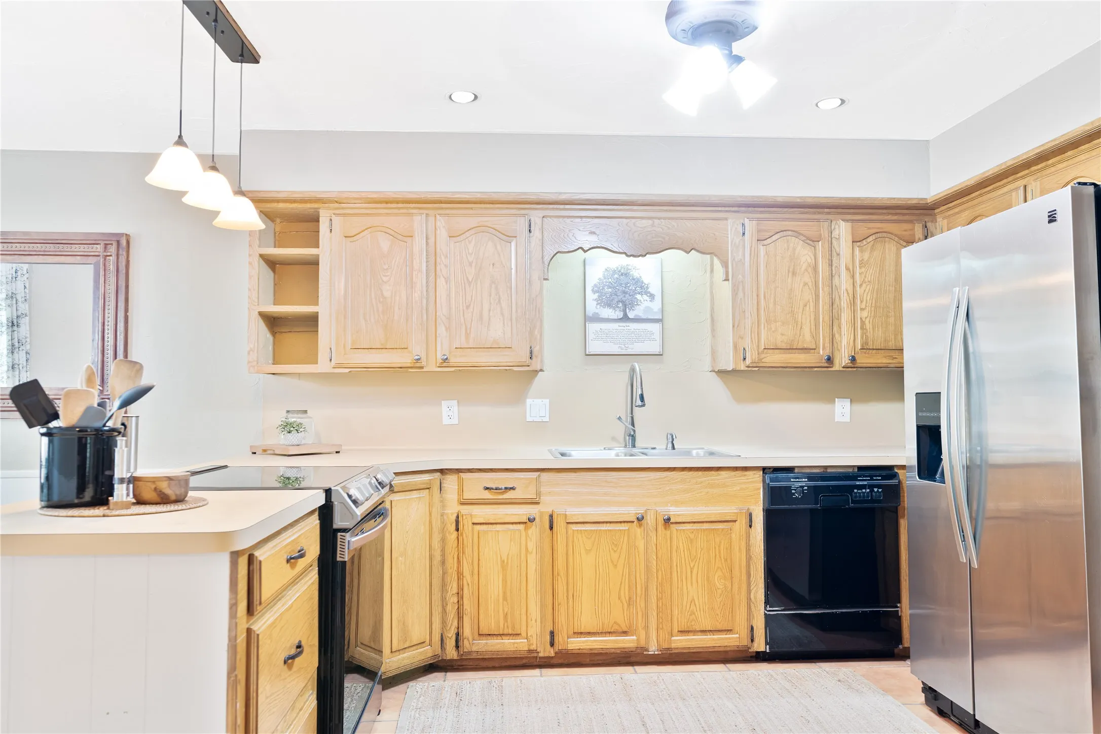 Kitchen featuring wood cabinetry, a stainless steel refrigerator, a black dishwasher, and a stainless steel range