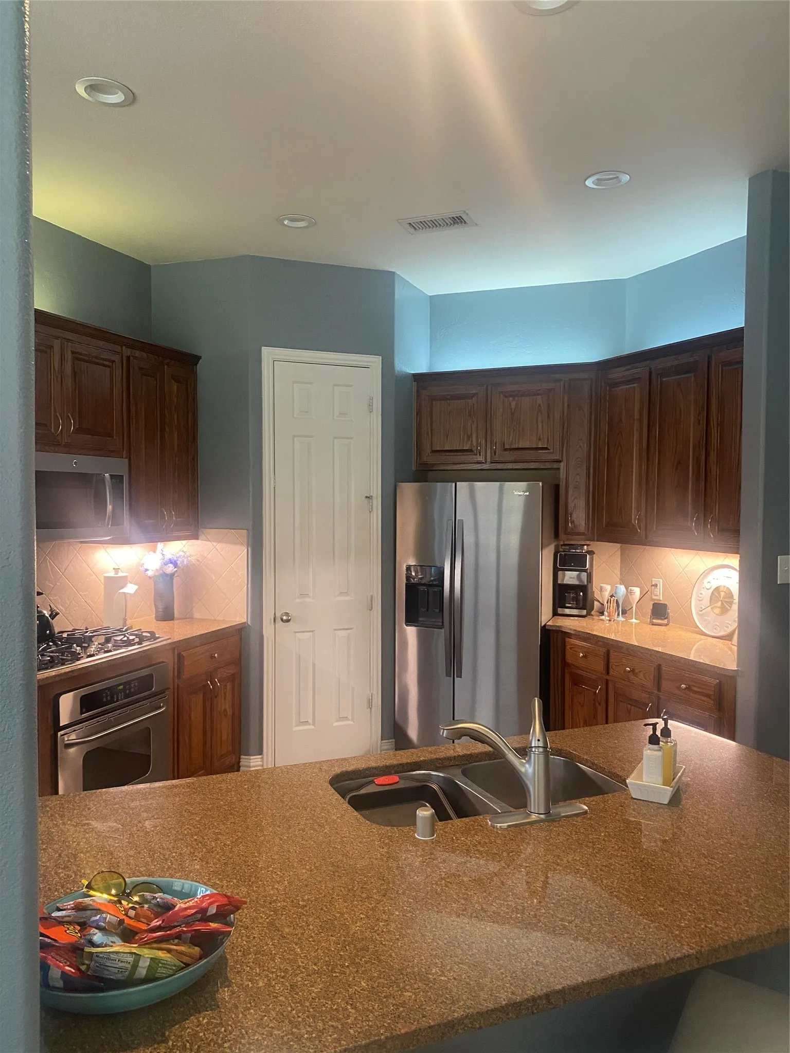 Kitchen featuring stainless steel appliances, wood cabinetry, recessed lighting, and a double basin sink