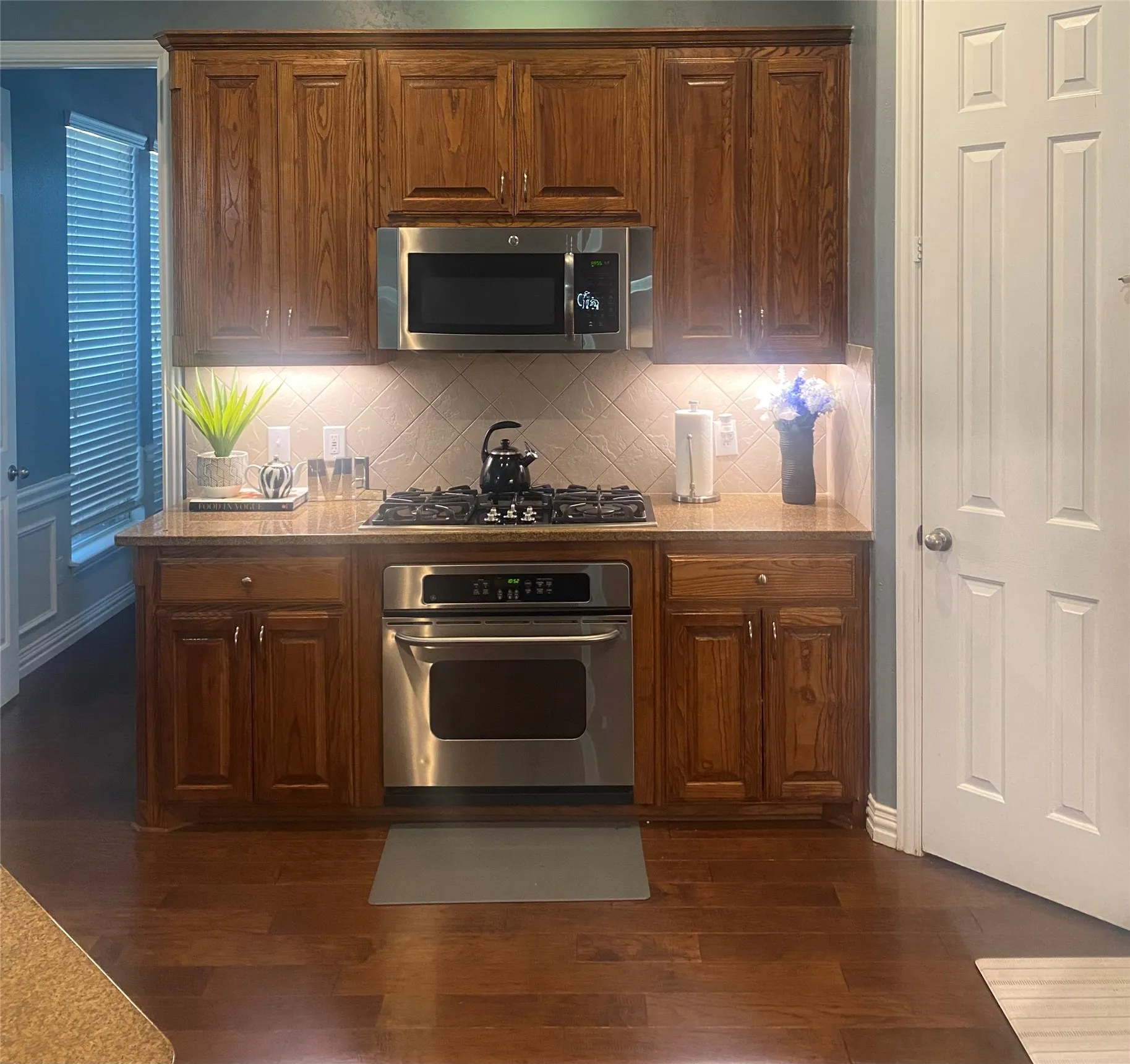 Wood-finish flooring with a built-in oven, gas cooktop, and microwave