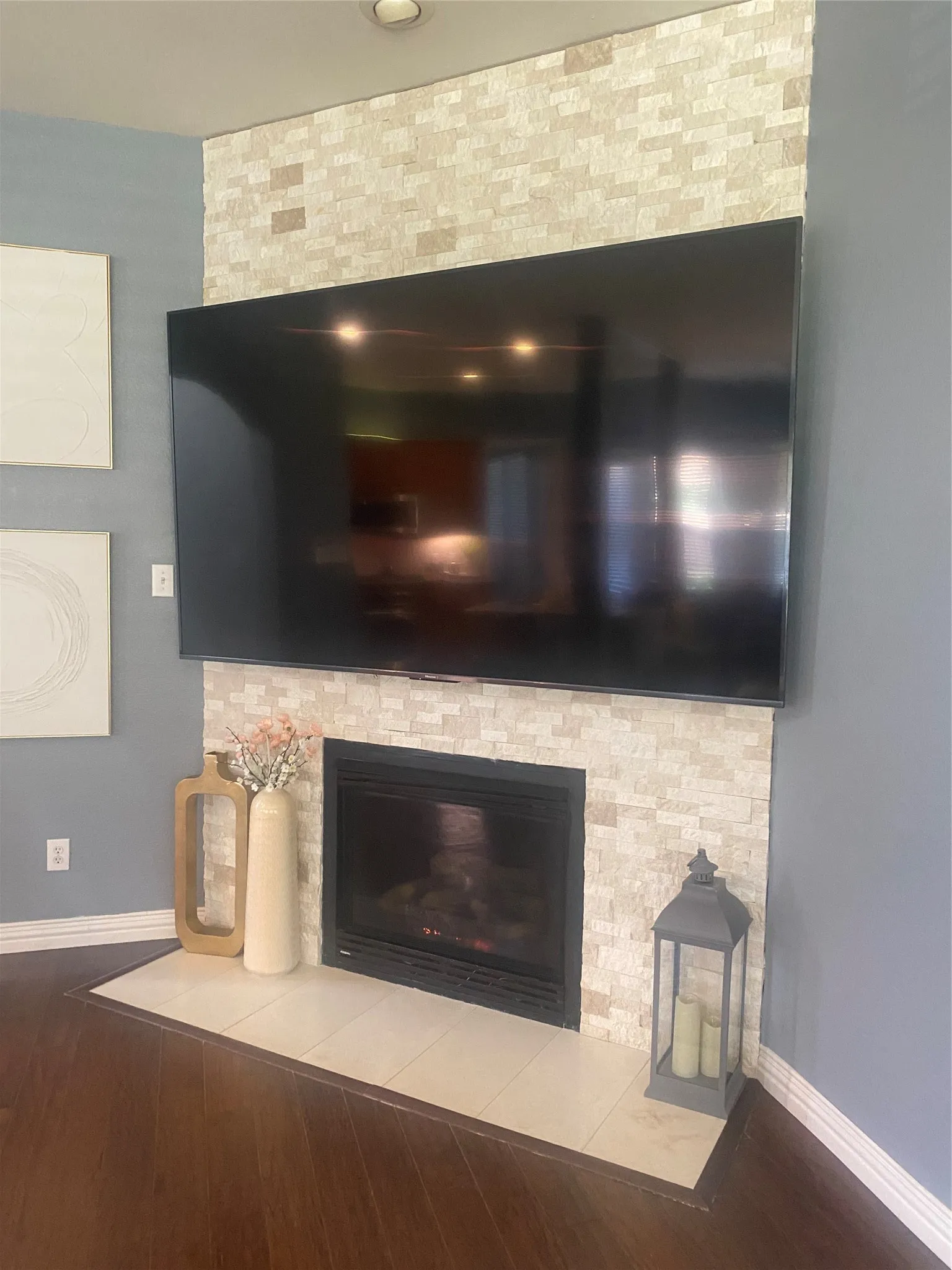 Corner fireplace with a stone tile surround, black firebox, and a tiled hearth