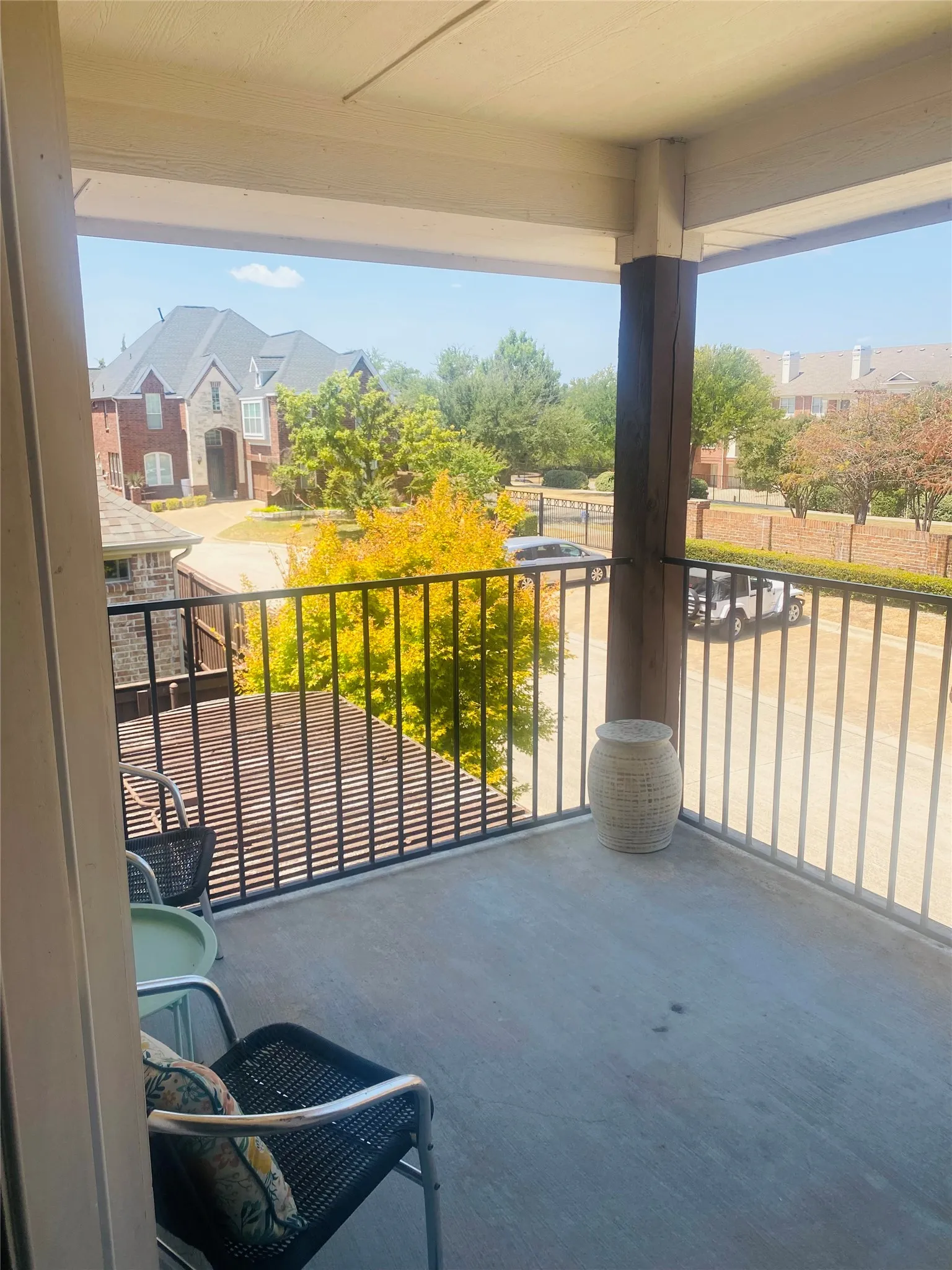 Balcony with a concrete surface, black metal railings, and a prominent wood-clad column