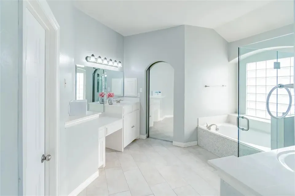 Spacious bathroom featuring a glass-enclosed shower, a separate soaking tub with mosaic tile surround, and a double vanity with an integrated makeup counter