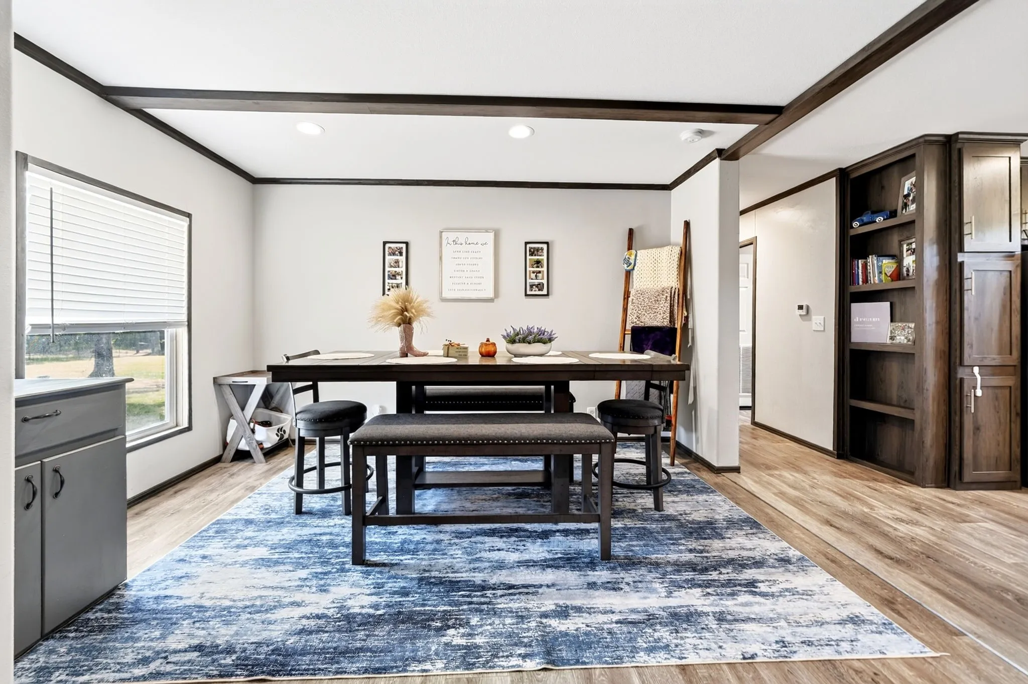 Spacious interior with wood-finish flooring, recessed lighting, built-in shelving, and exposed dark wood beams