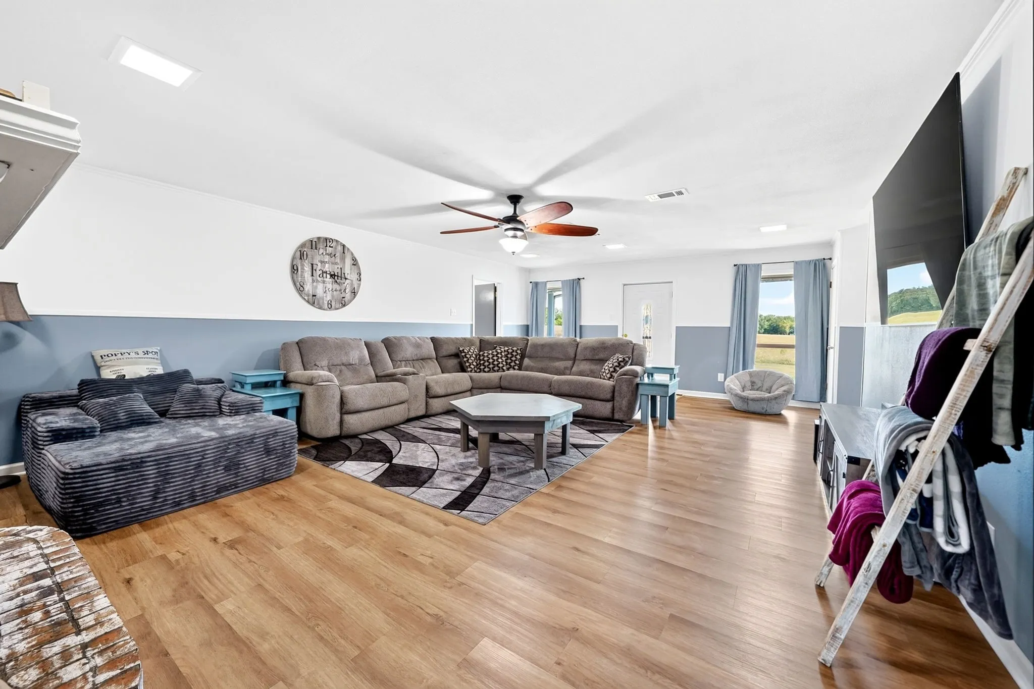 Spacious living area featuring wood-finish flooring, a ceiling fan, and recessed lighting