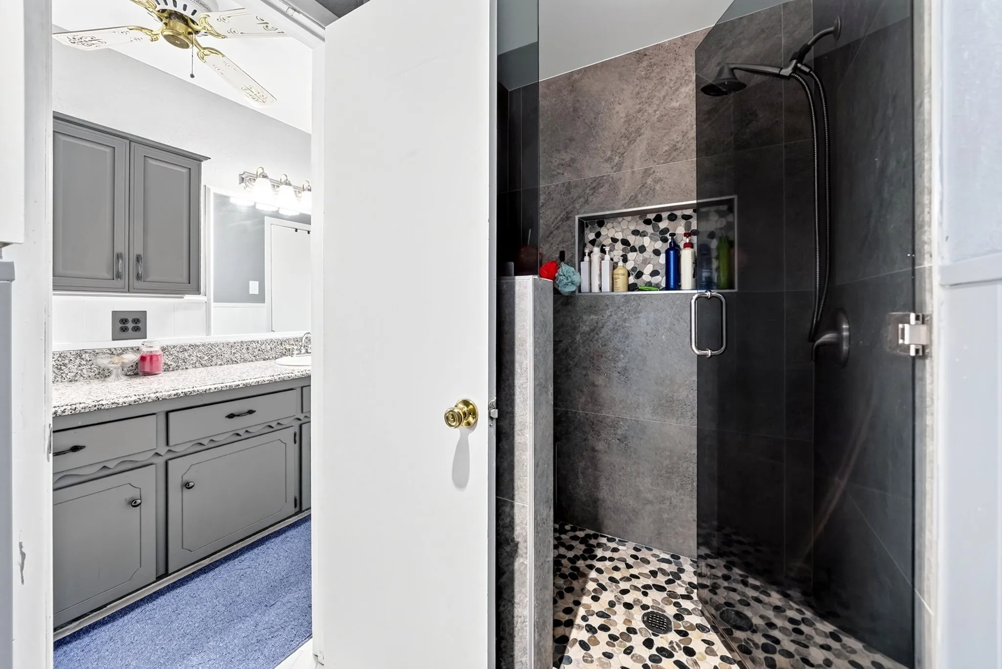 Walk-in shower with textured tile surround and river rock flooring