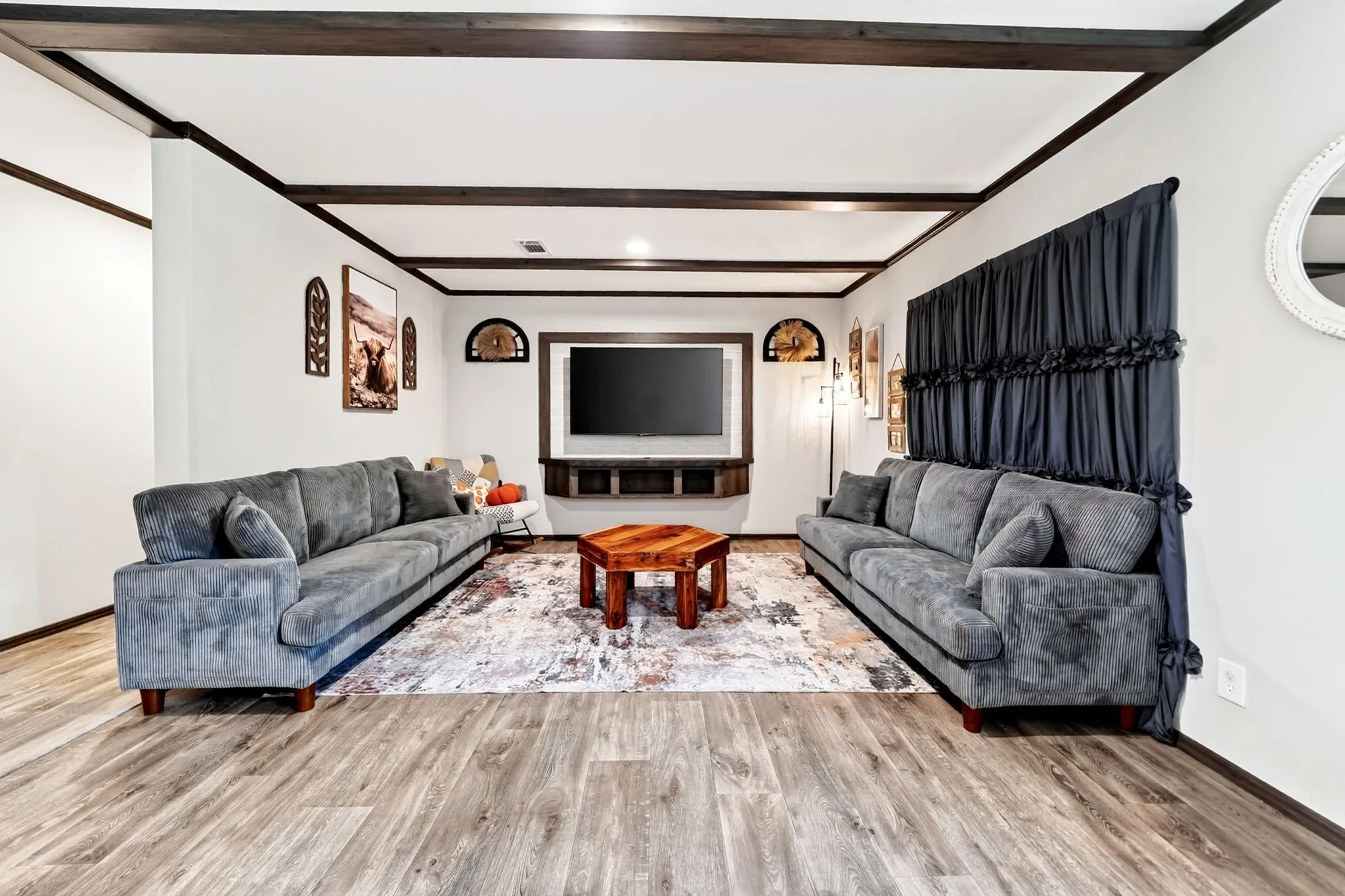 Wood-finish flooring throughout, exposed ceiling beams, and a built-in media console