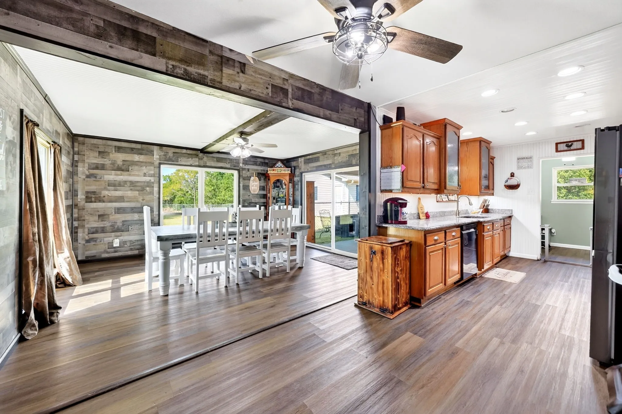 Open-concept kitchen and dining area featuring wood-finish flooring, wood cabinetry, and a ceiling fan with integrated lighting