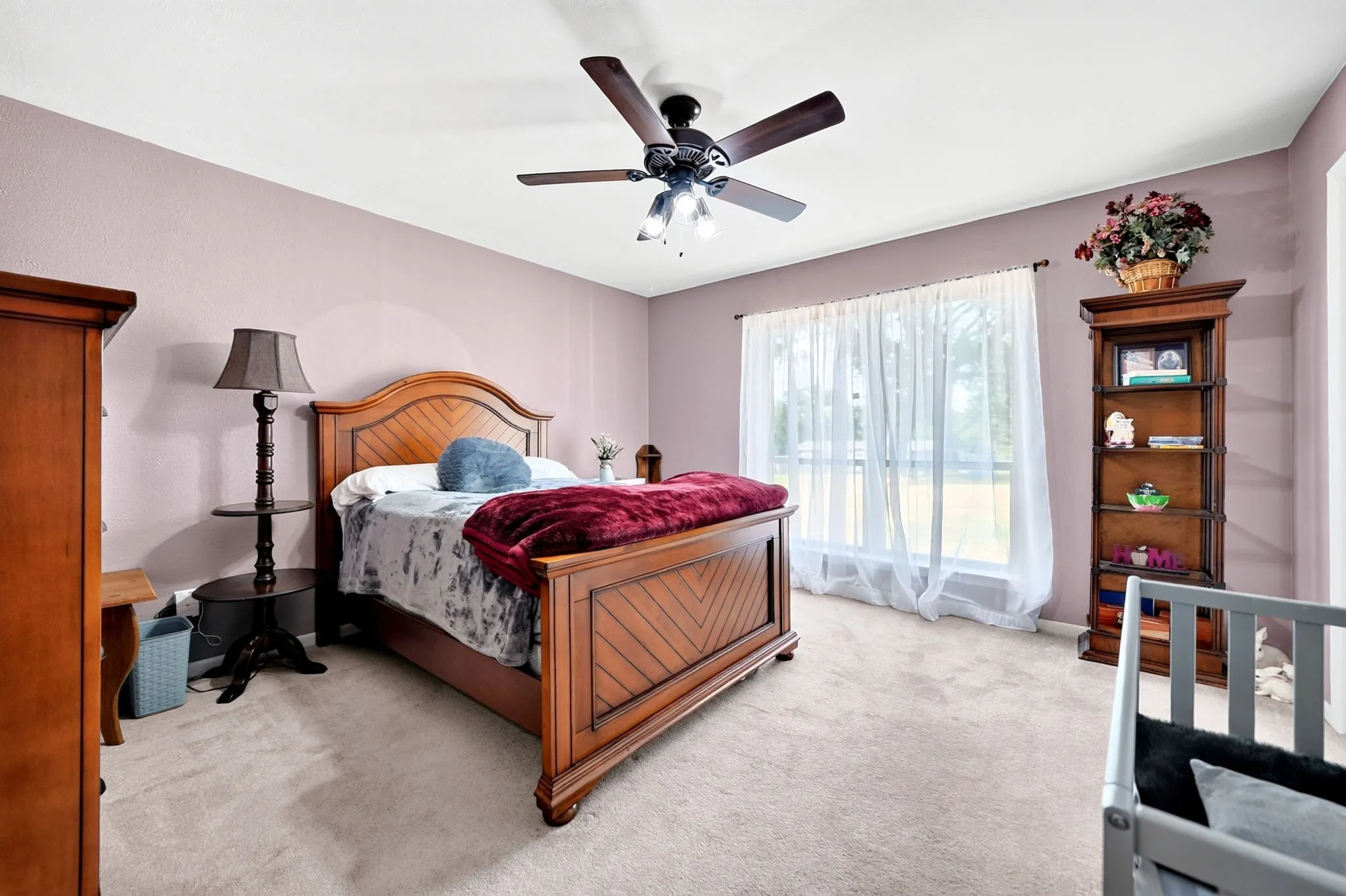 Ceiling fan with integrated lighting, window with sheer curtains, neutral carpeting, and light-toned walls