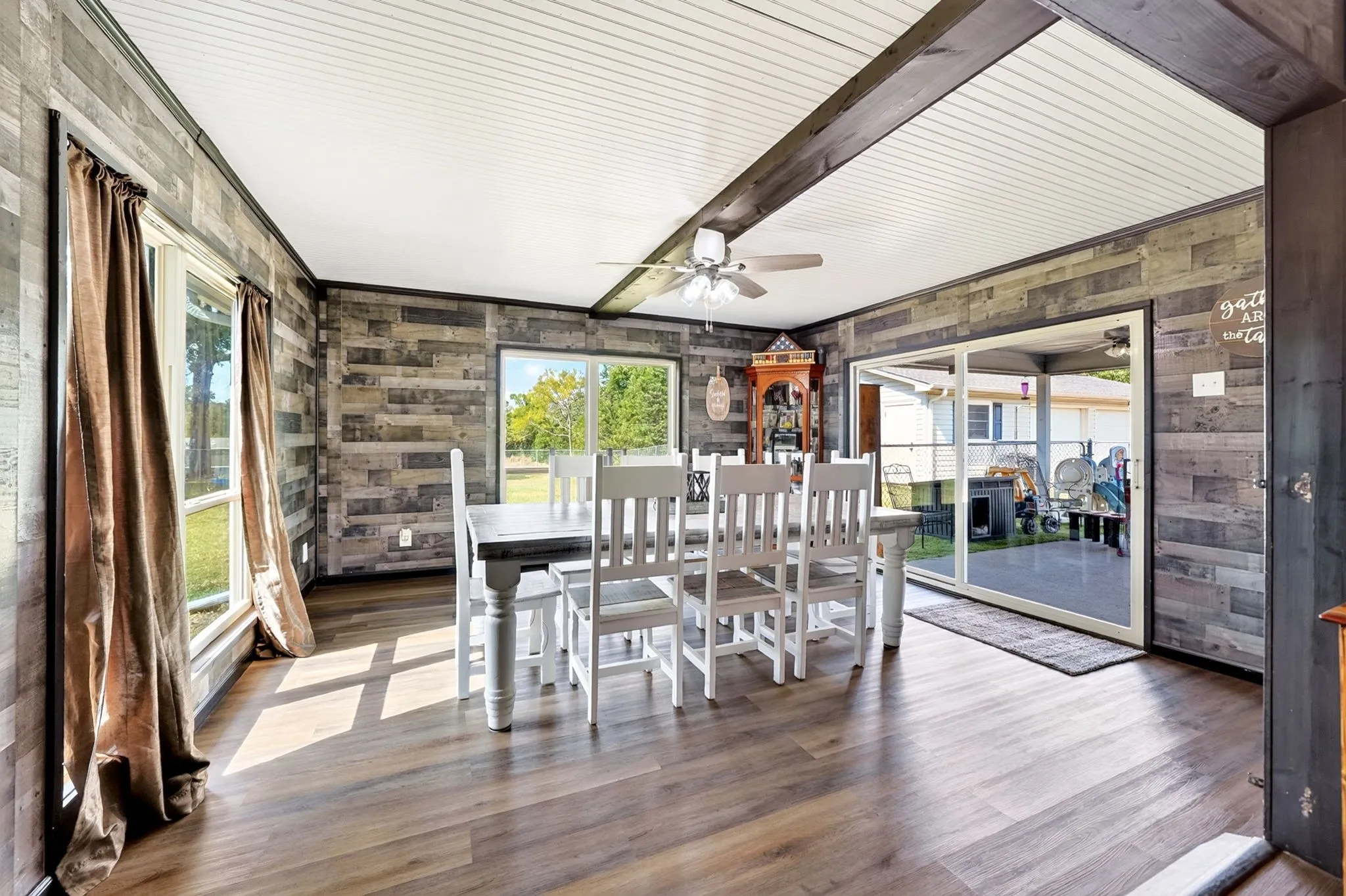 Wood-finish flooring with plank-style wall covering, dual windows, and ceiling fan