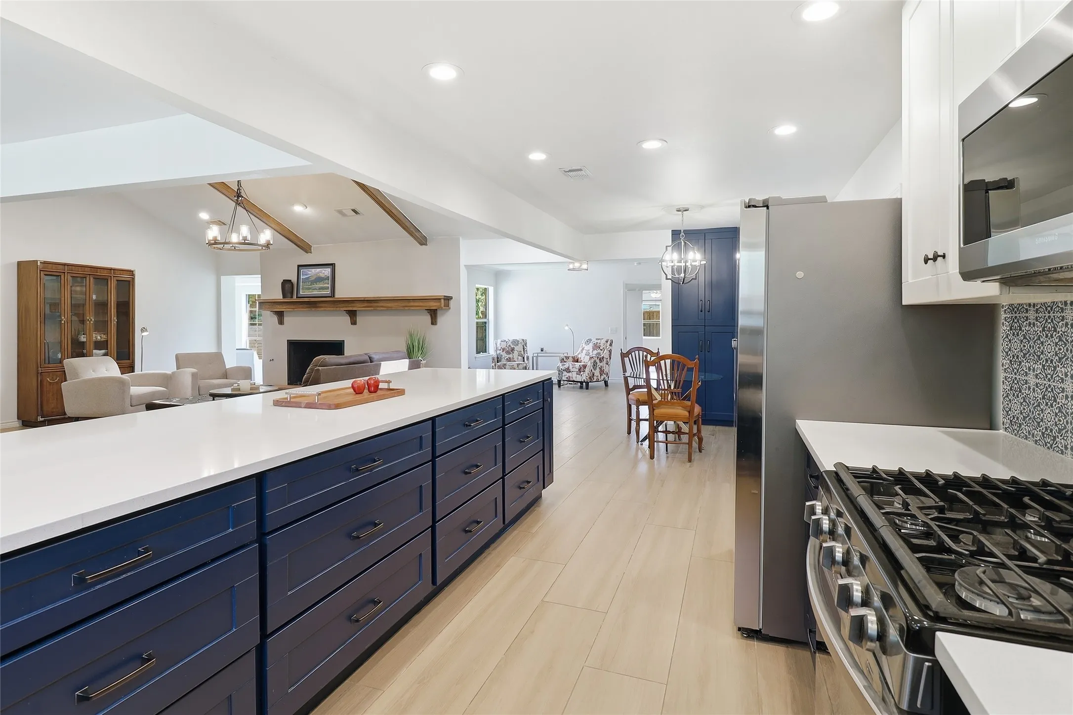 Spacious kitchen island with extensive storage, stainless steel appliances, wood-finish flooring, recessed lighting, and an open concept layout