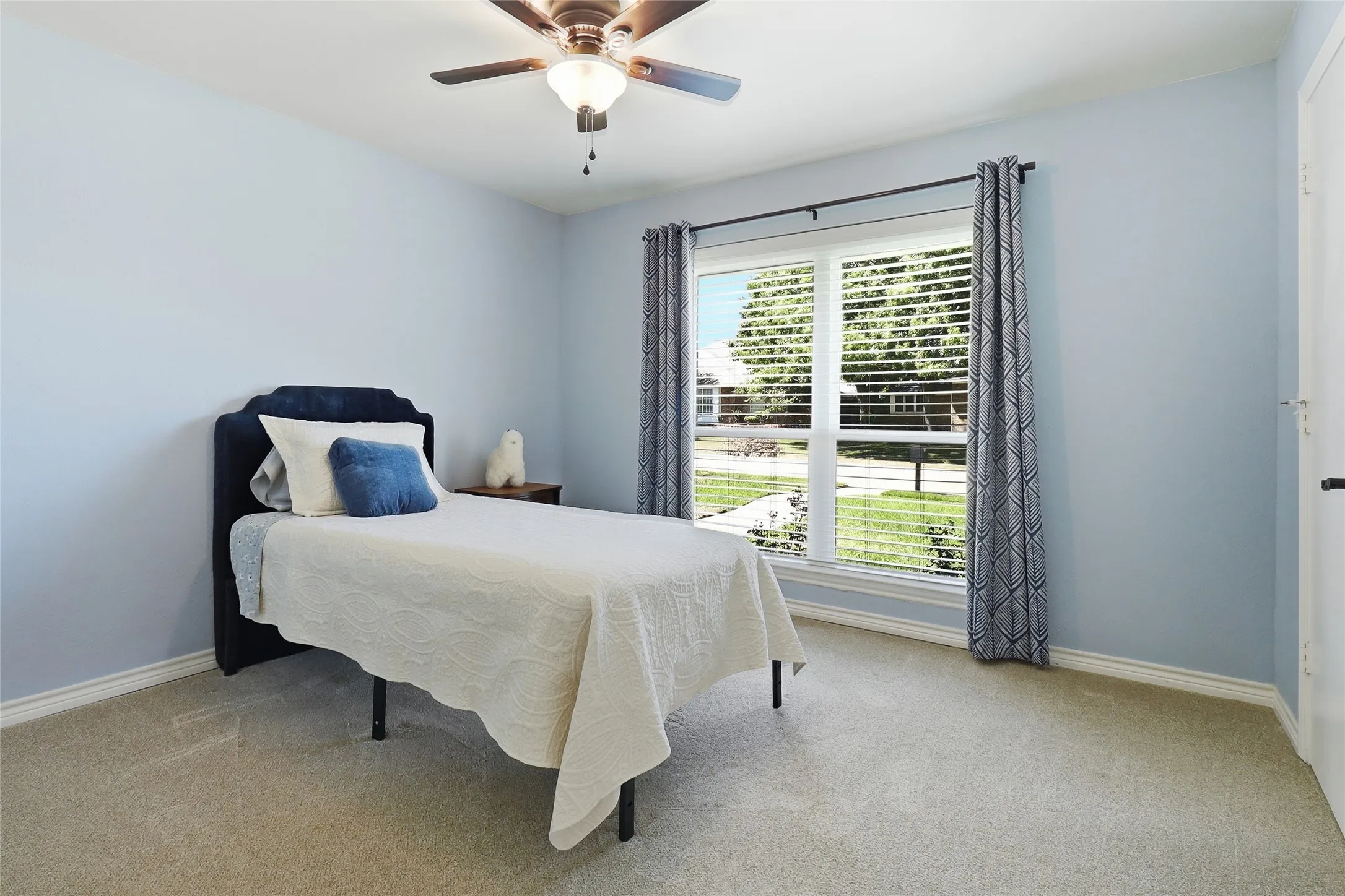 Carpeted flooring, a ceiling fan with integrated lighting, window blinds, and a white paneled door