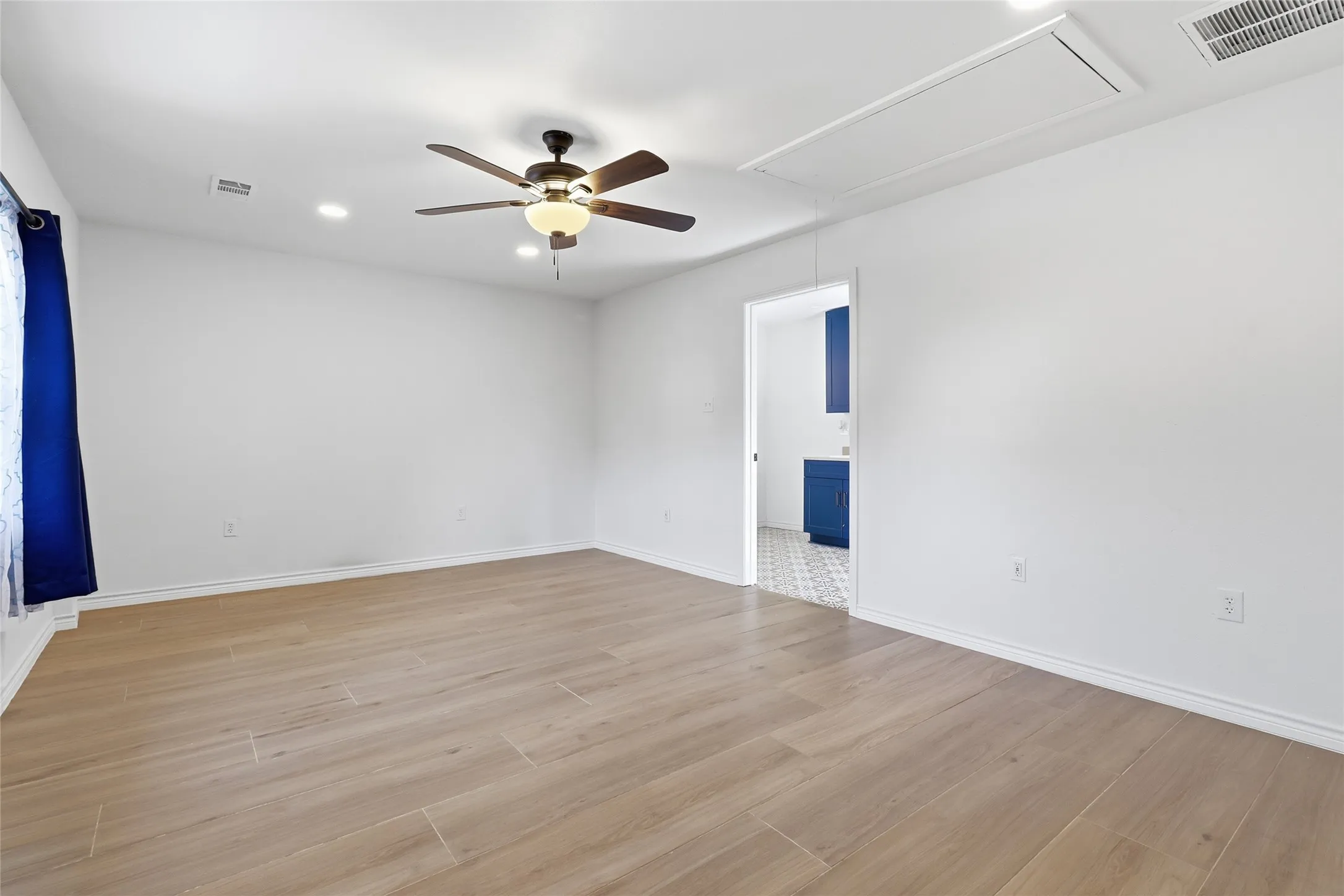 Enclosed garage that could be used as another office or workroom. Wood-finish flooring with white walls and recessed ceiling lighting