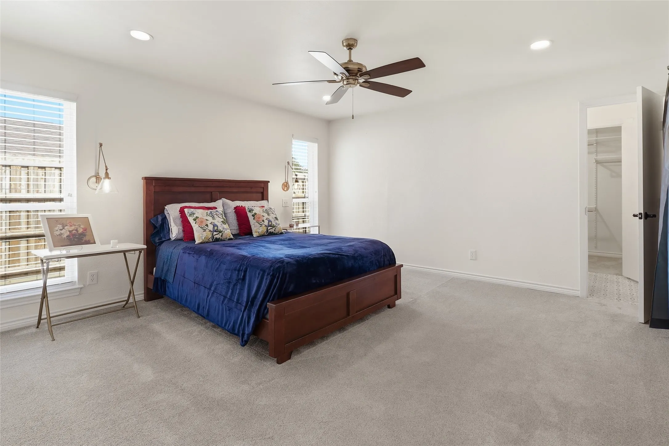 Master bedroom with recessed lighting, ceiling fan with light, light-colored carpeting, multiple windows with blinds.