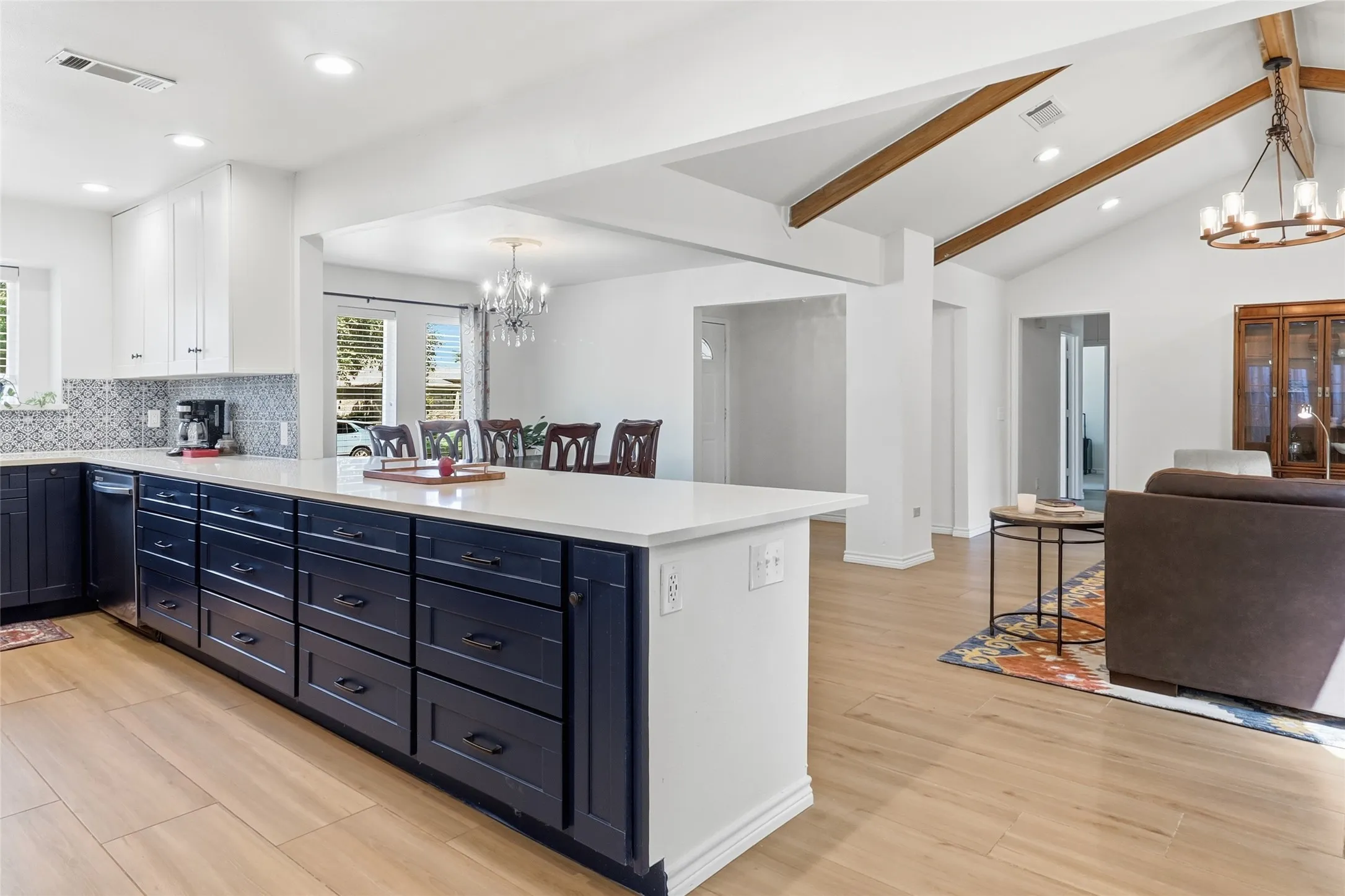 Spacious kitchen with a large central island, white , quartz countertops, two-tone cabinetry, and wood-finish flooring