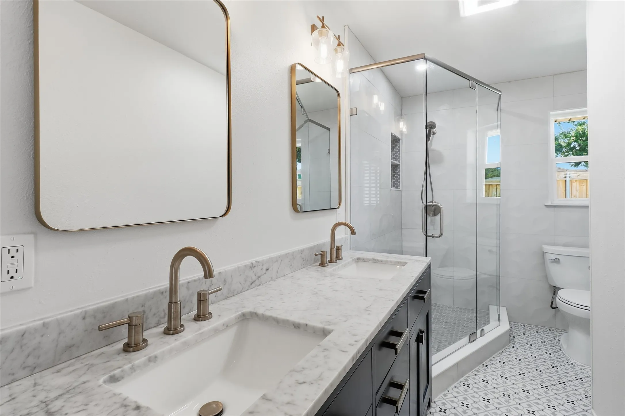 Dual vanity with undermount sinks, marble-patterned countertop, and brass-finish fixtures