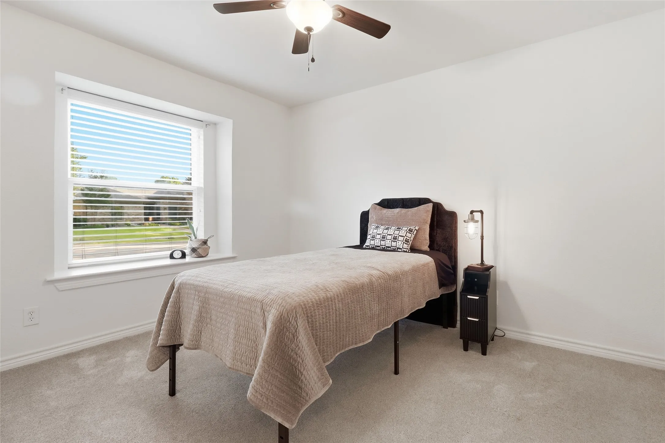 Carpeted room with a ceiling fan and a window featuring horizontal blinds