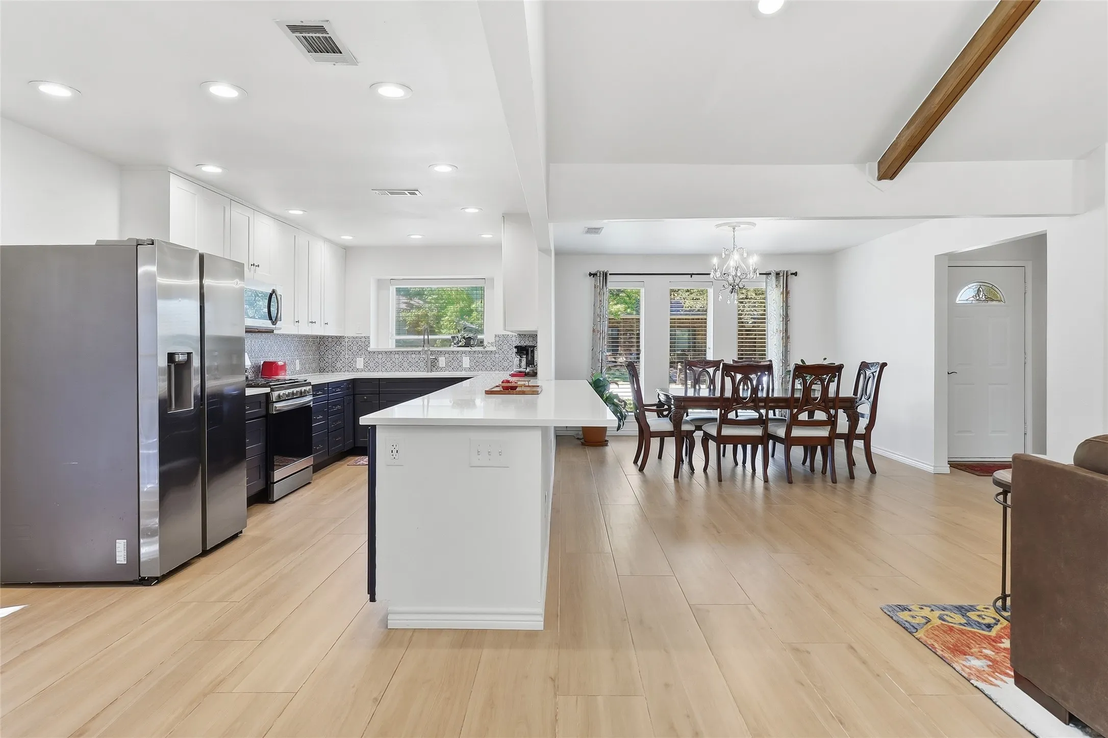 Open-concept kitchen and dining area featuring light wood-finish flooring, recessed lighting, and a kitchen island with a light-toned countertop.  Stainless steal appliances.