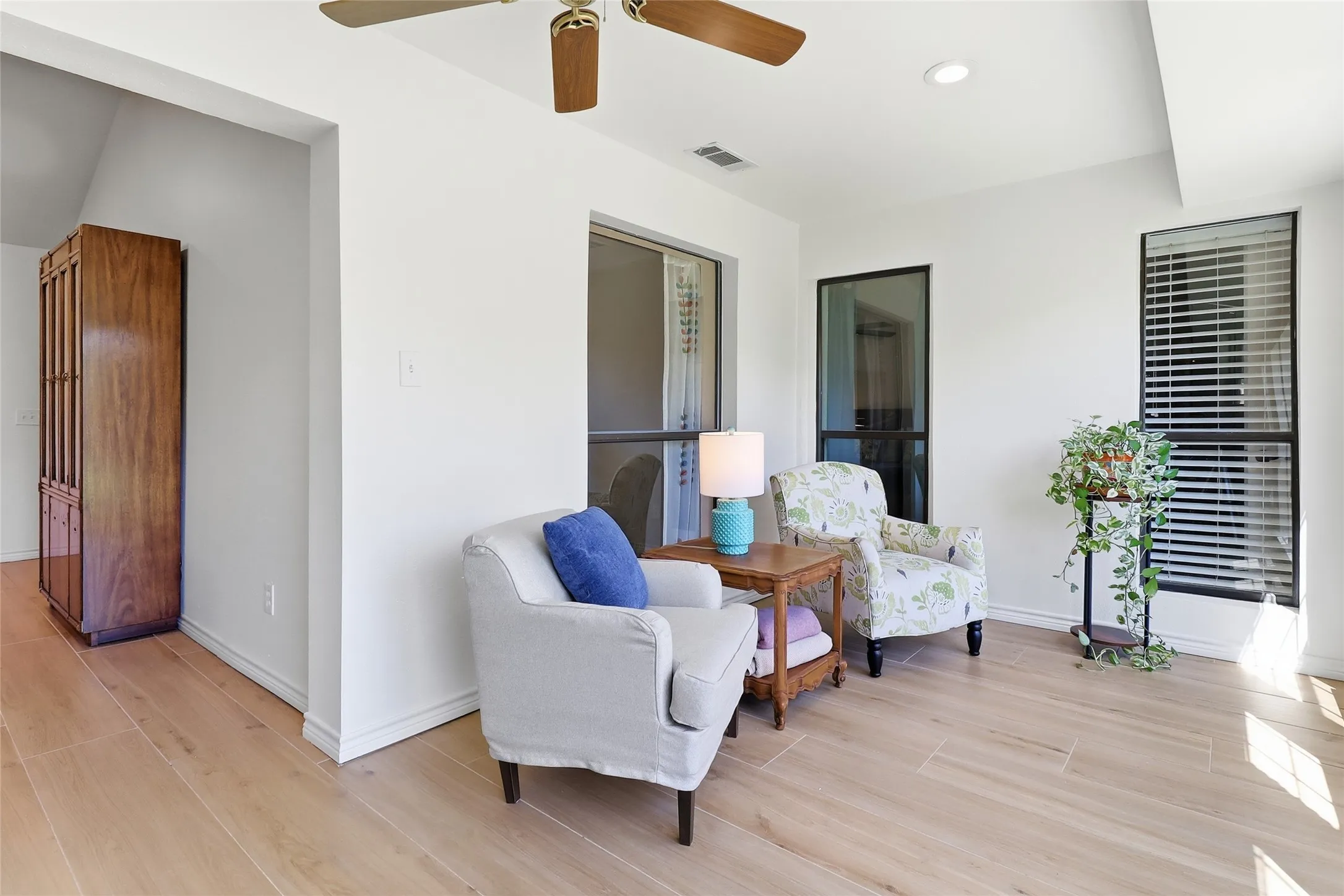Wood-finish flooring throughout, bright white walls, recessed lighting, and a ceiling fan with integrated lighting