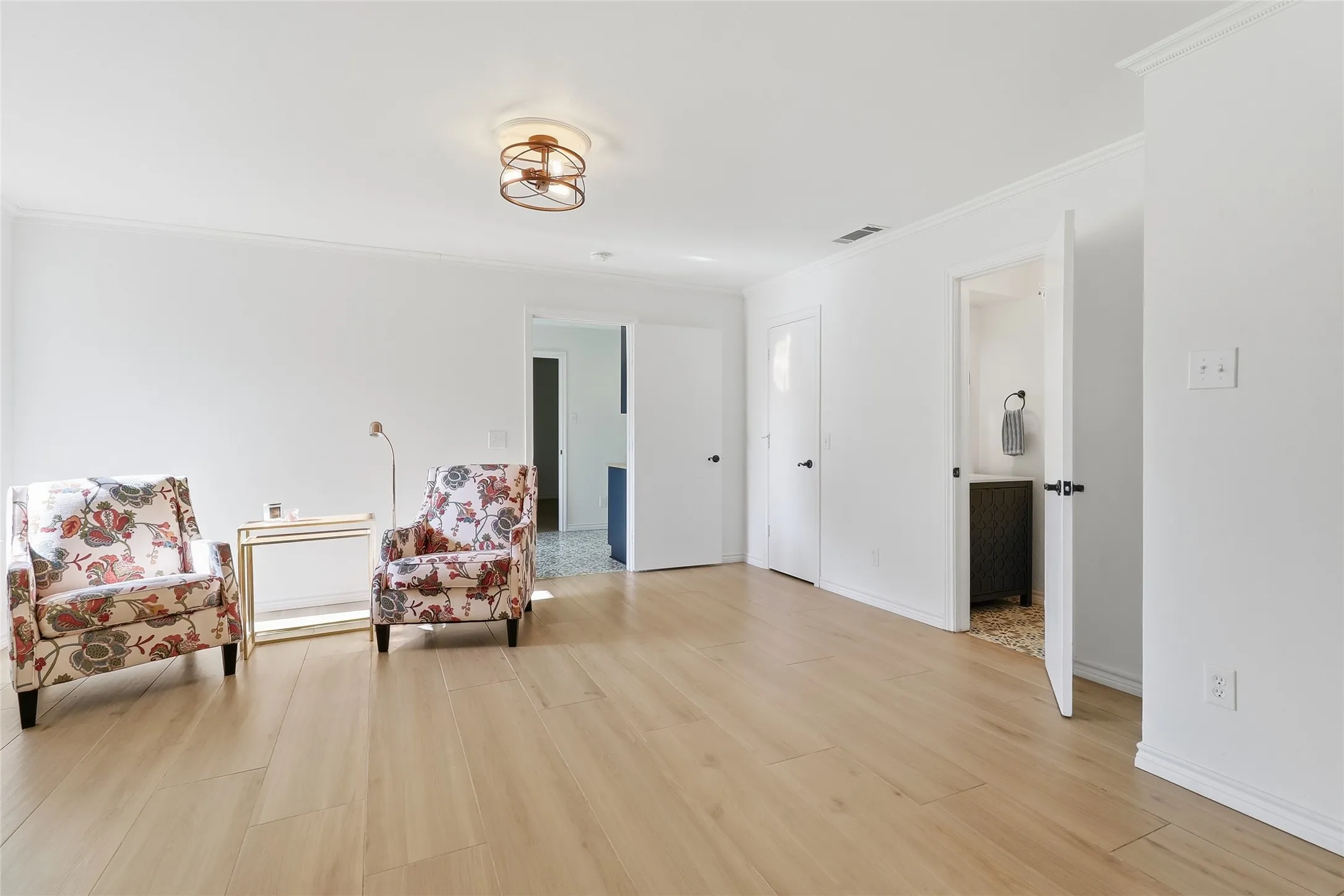 Wide plank wood-finish flooring, white walls, flush mount ceiling light, and interior doors with black hardware.  Leads to bedrooms and large laundry room.