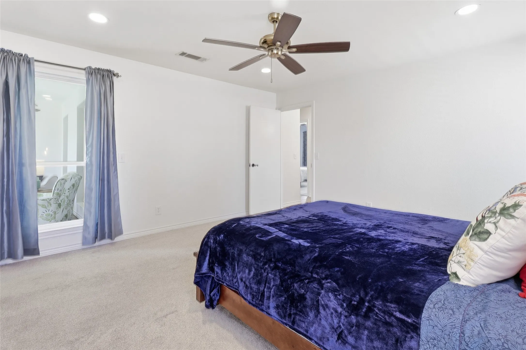 Spacious master bedroom featuring a ceiling fan, recessed lighting, and soft carpet flooring