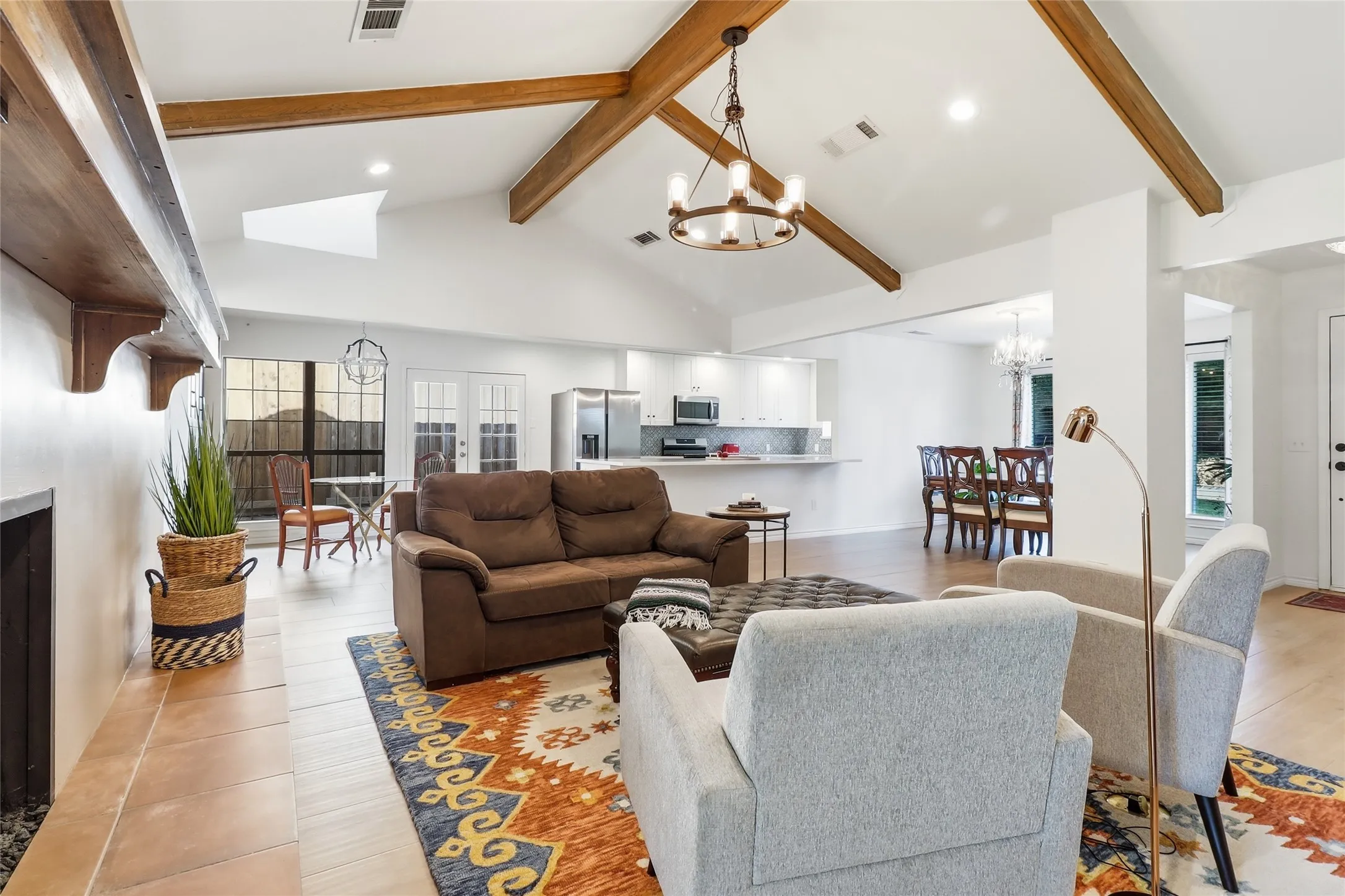 Vaulted ceiling with exposed wood beams, skylight, recessed lighting, wood-finish flooring, and a built-in fireplace with a wood mantle