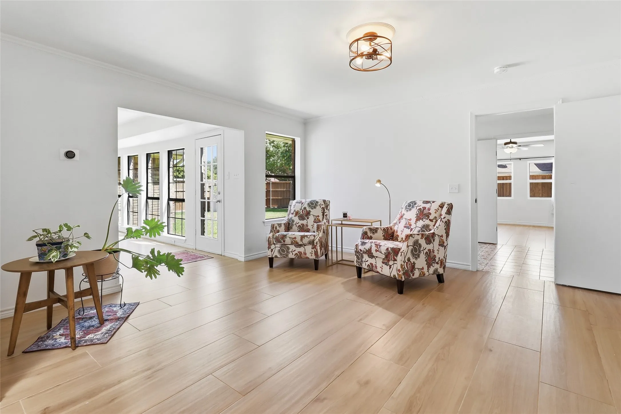 Light wood-finish flooring, white walls, recessed lighting, and a contemporary ceiling light fixture.  Could be used as a second living area or game room also.