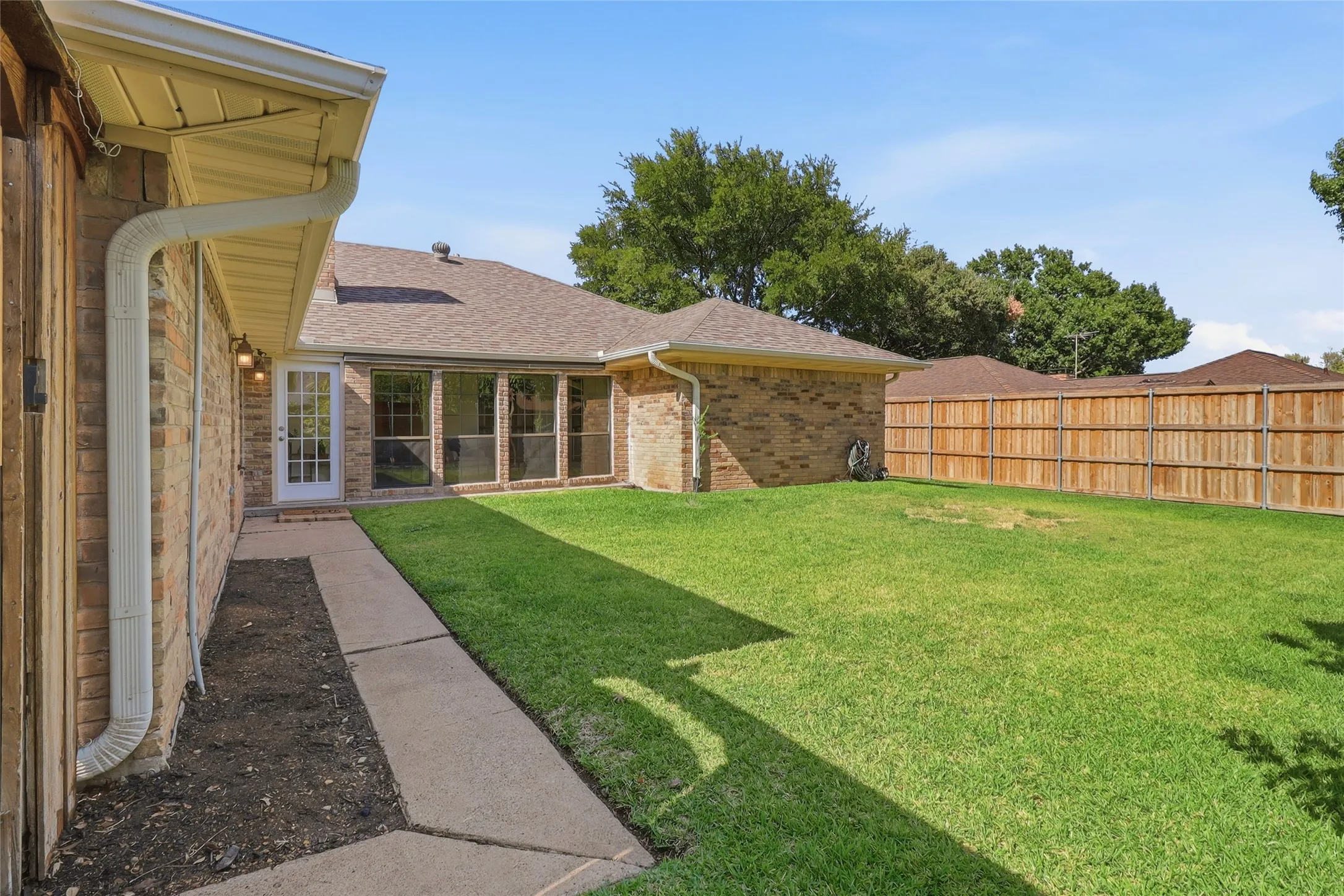 Expansive grassy yard with a wood privacy fence