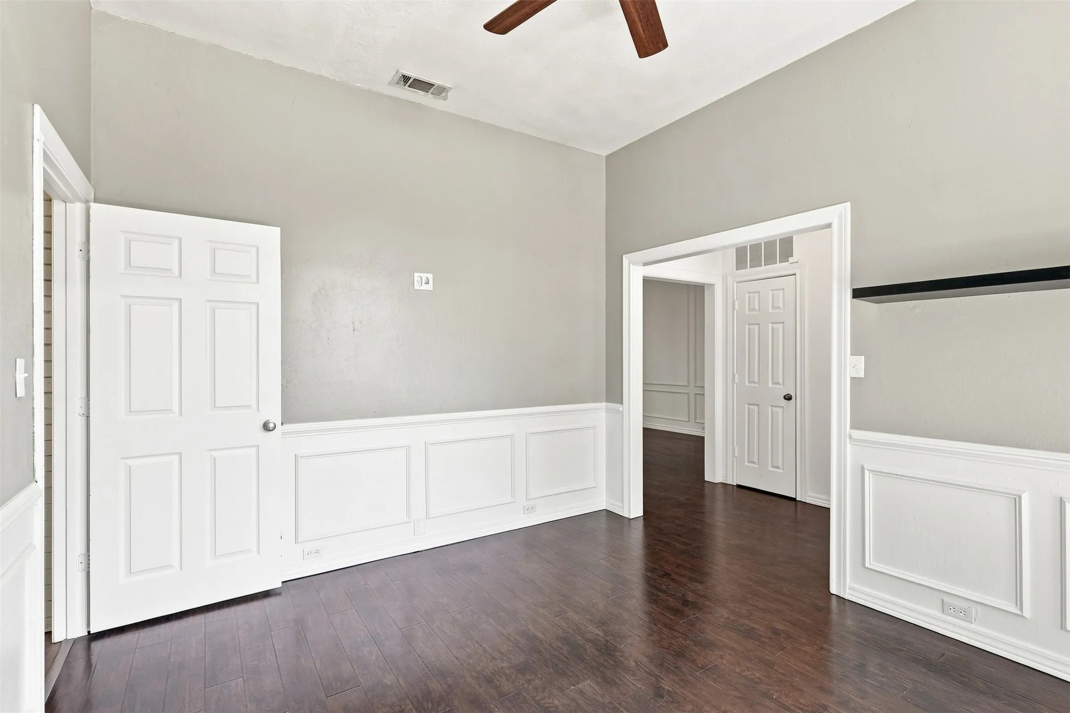 Wood-finish flooring, half-wall wainscoting, vaulted ceiling, and ceiling fan
