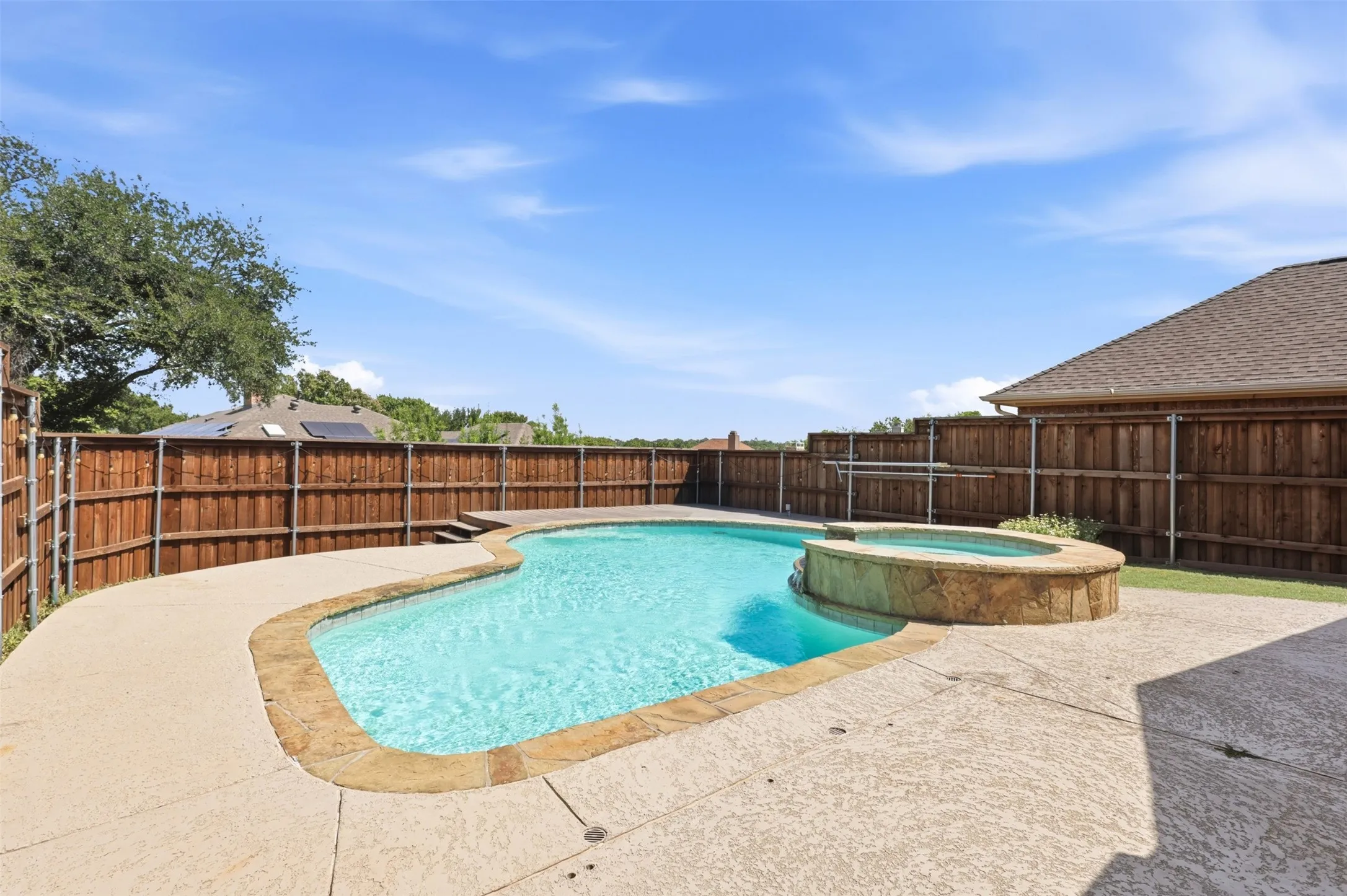Freeform swimming pool with integrated spa and stone-clad surround