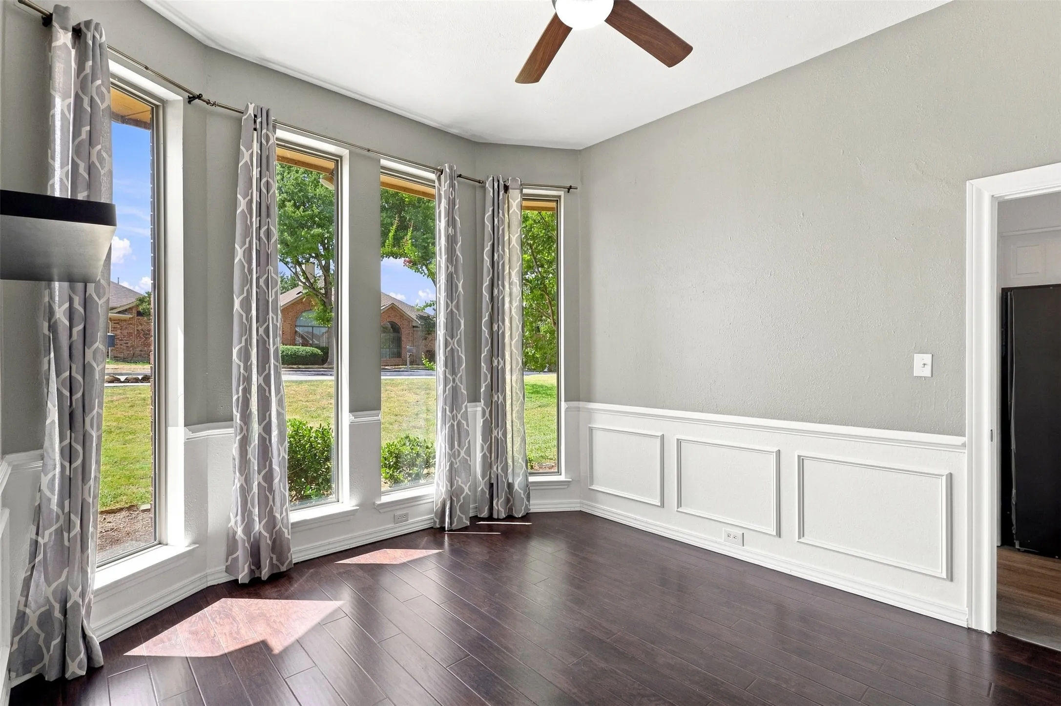 Wood-finish flooring, half-wall wainscoting, vaulted ceiling, and ceiling fan