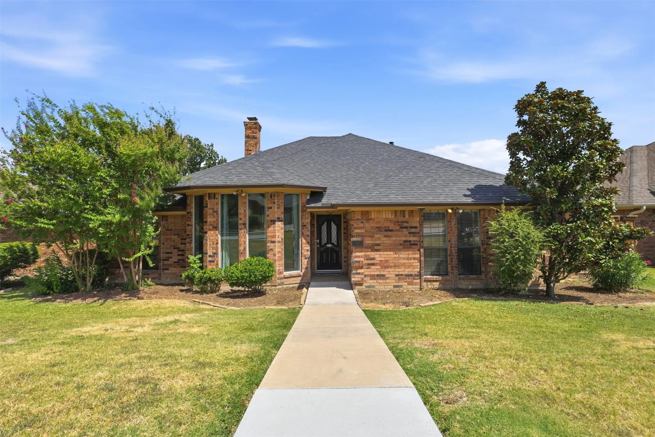 Brick exterior with a dark shingle roof