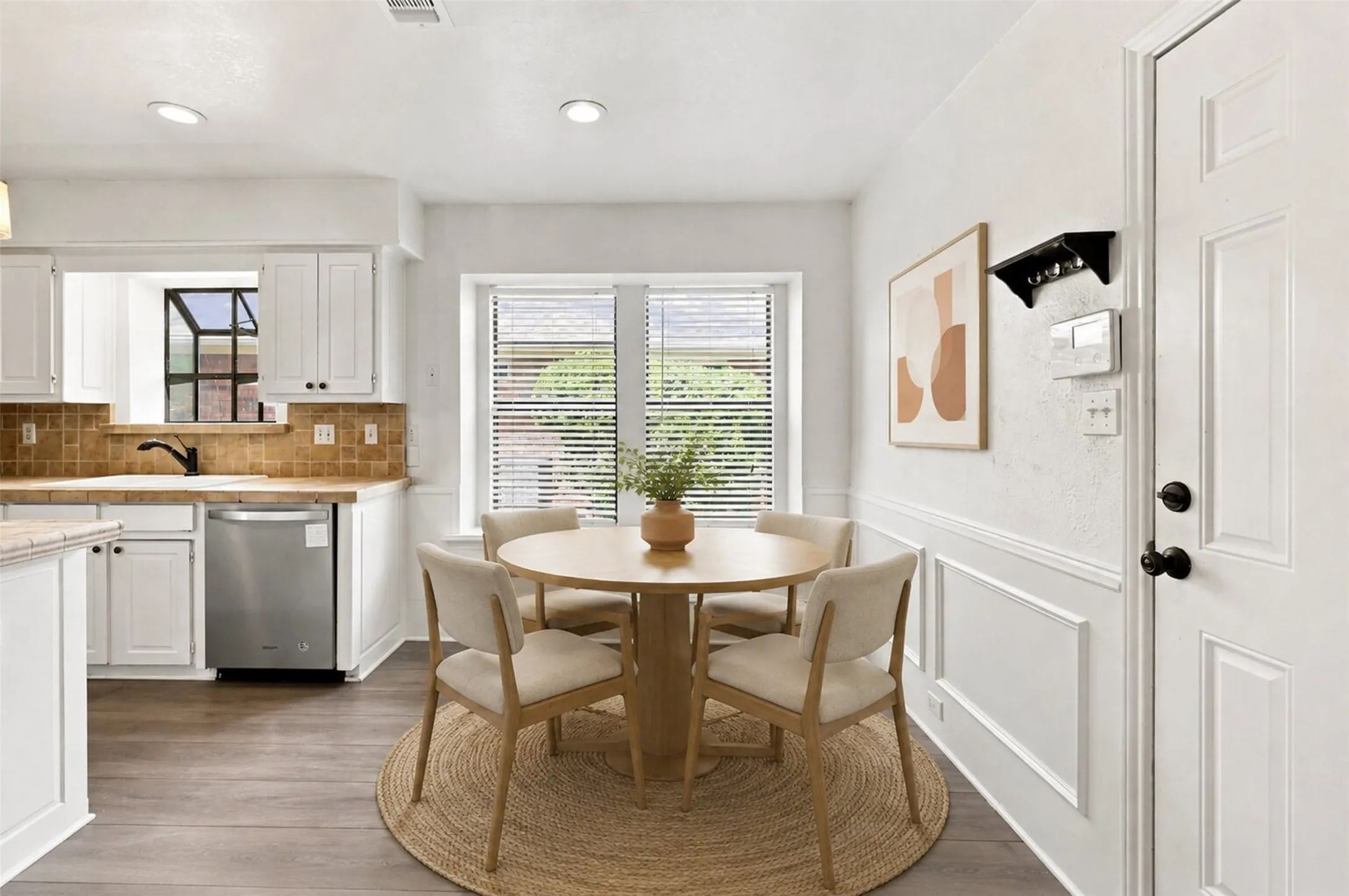Kitchen area with white cabinetry, stainless steel dishwasher, tile backsplash, and recessed lighting