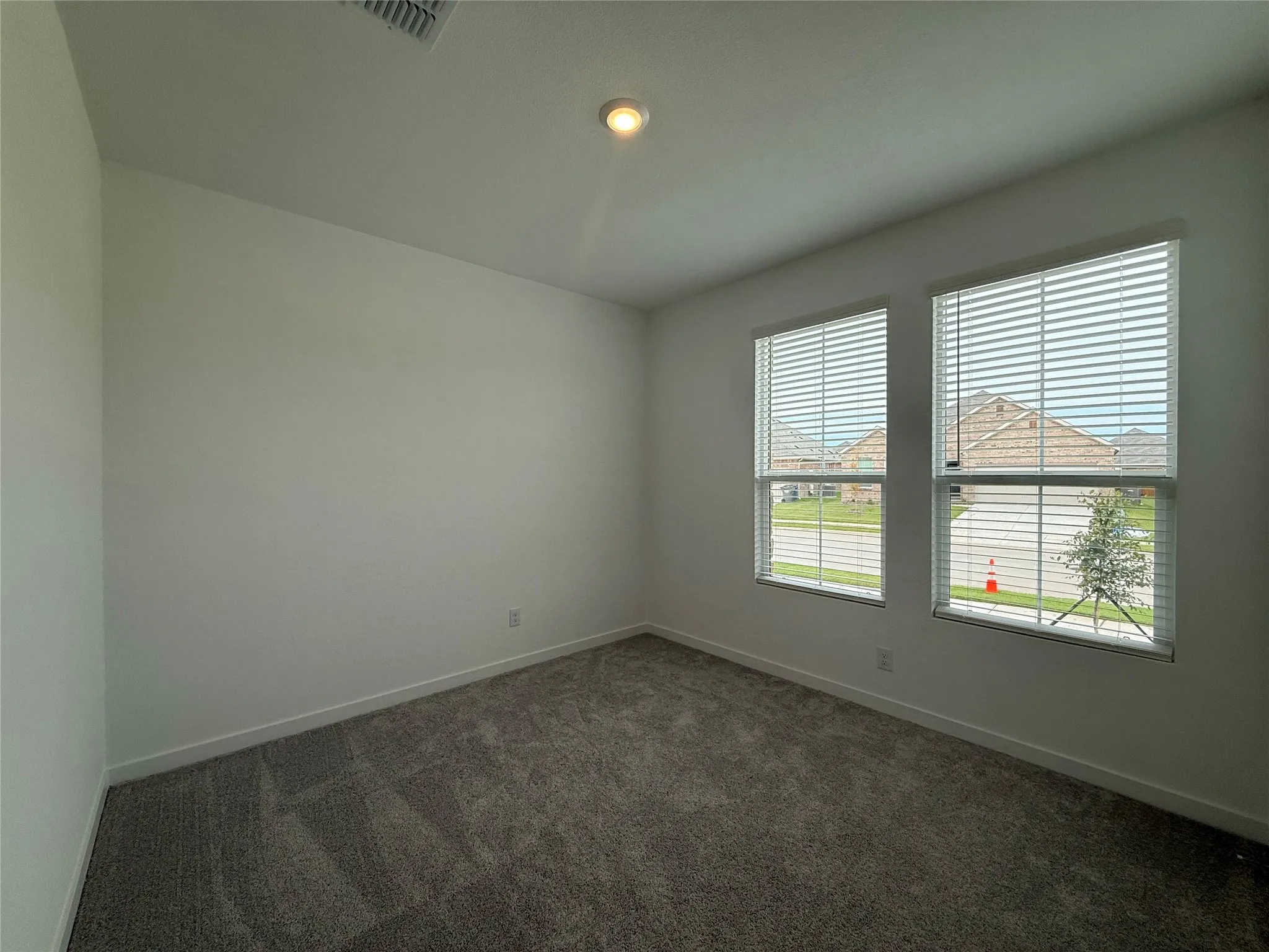 Neutral wall finishes, recessed ceiling lighting, two windows with blinds, and carpeted flooring