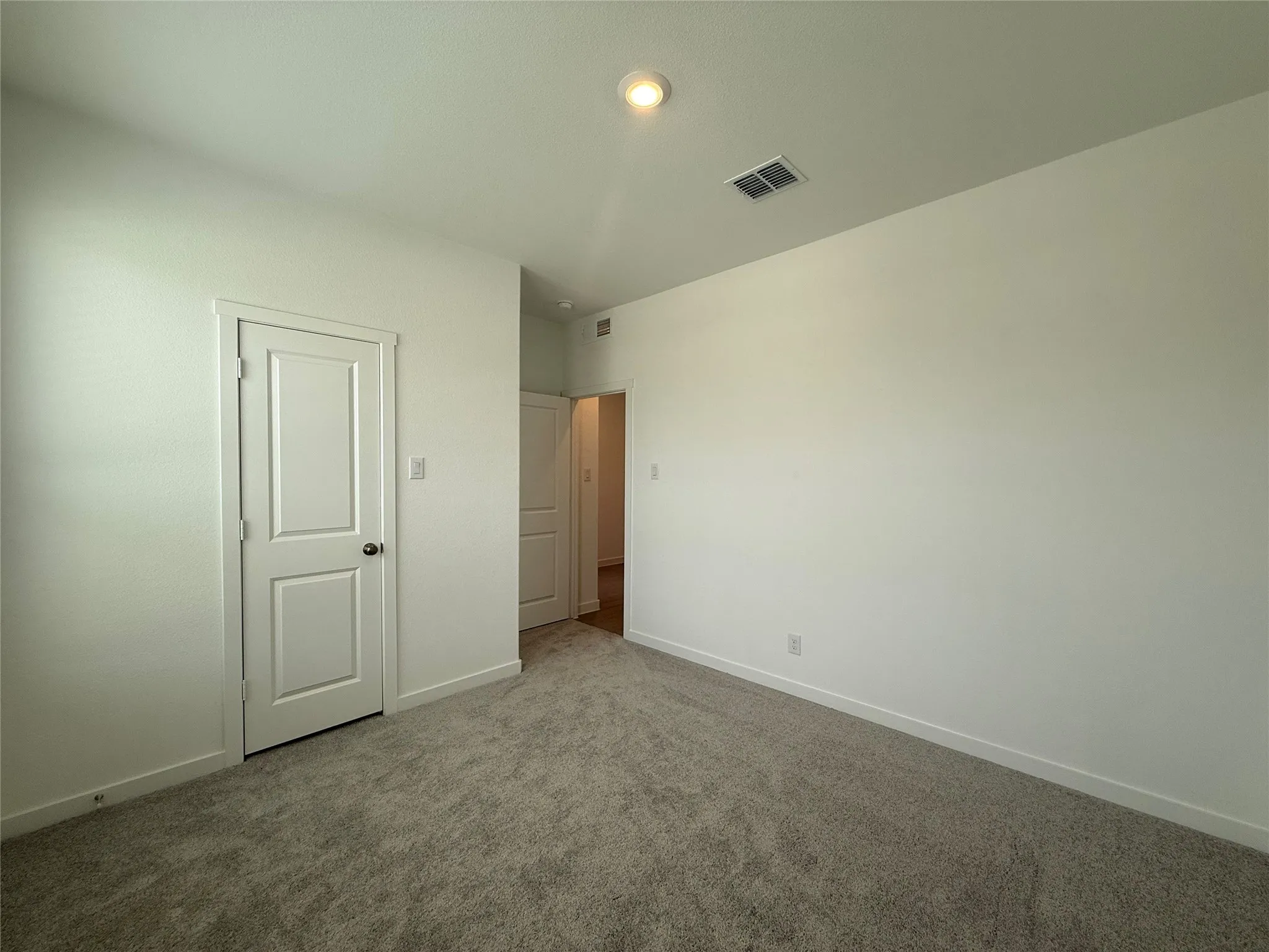 Recessed ceiling lighting, textured wall finishes, and gray carpet flooring